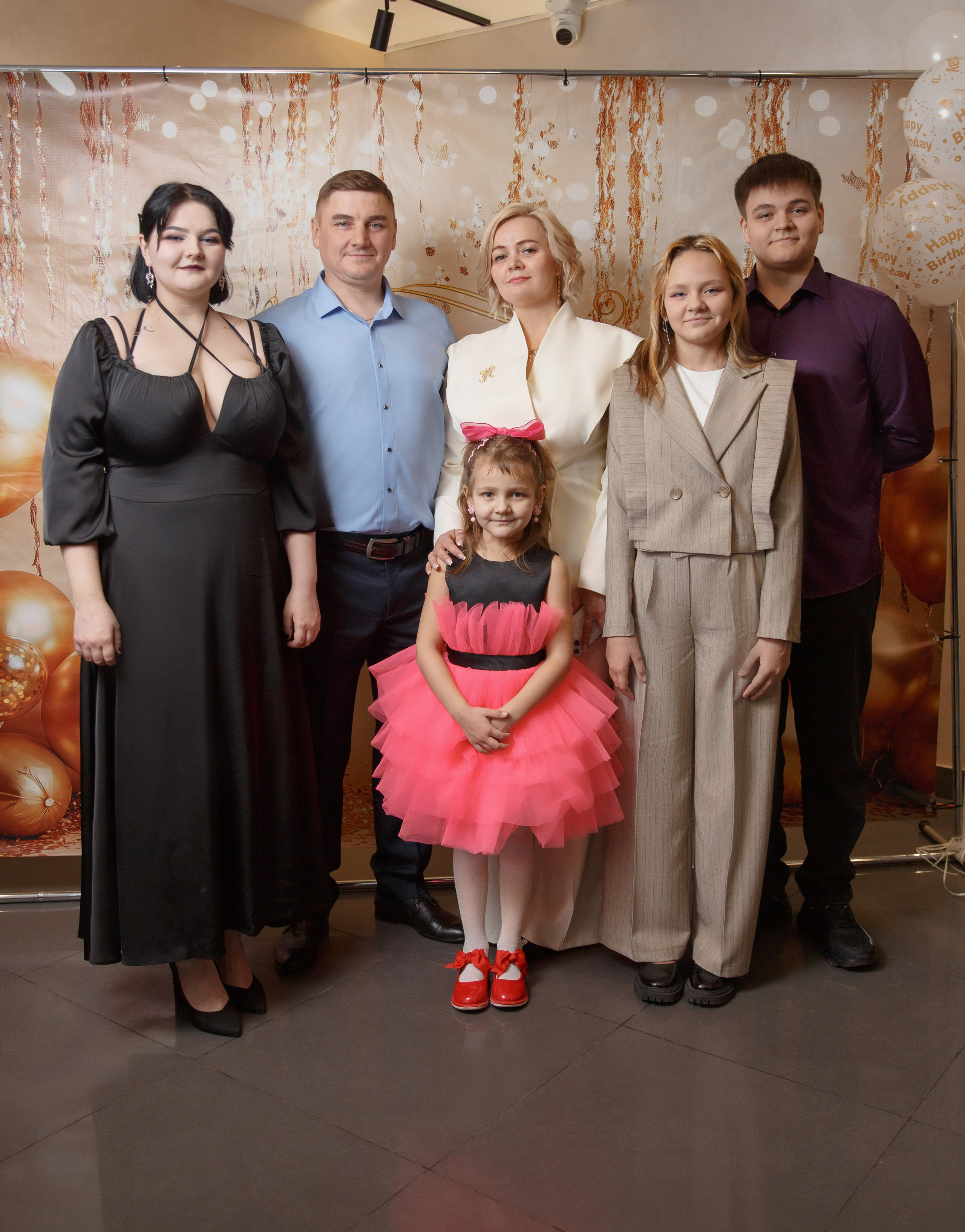 Семья с двумя детьми и родственниками позируют вместе.