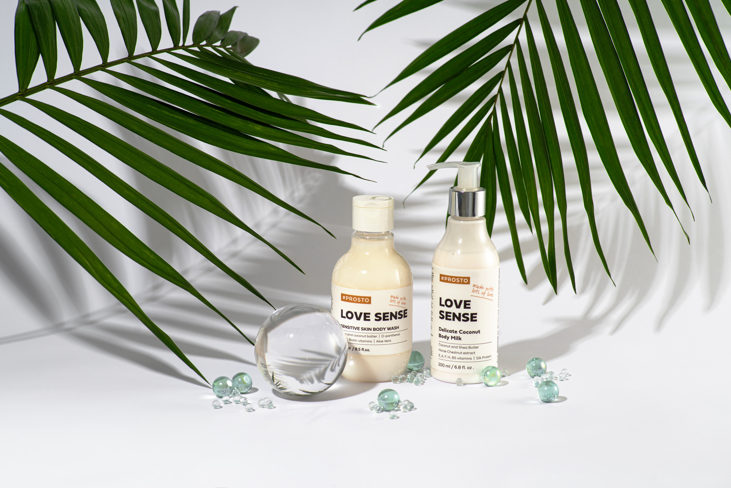 флакончики с косметикой на белом фоне в тени пальмовых листьев.