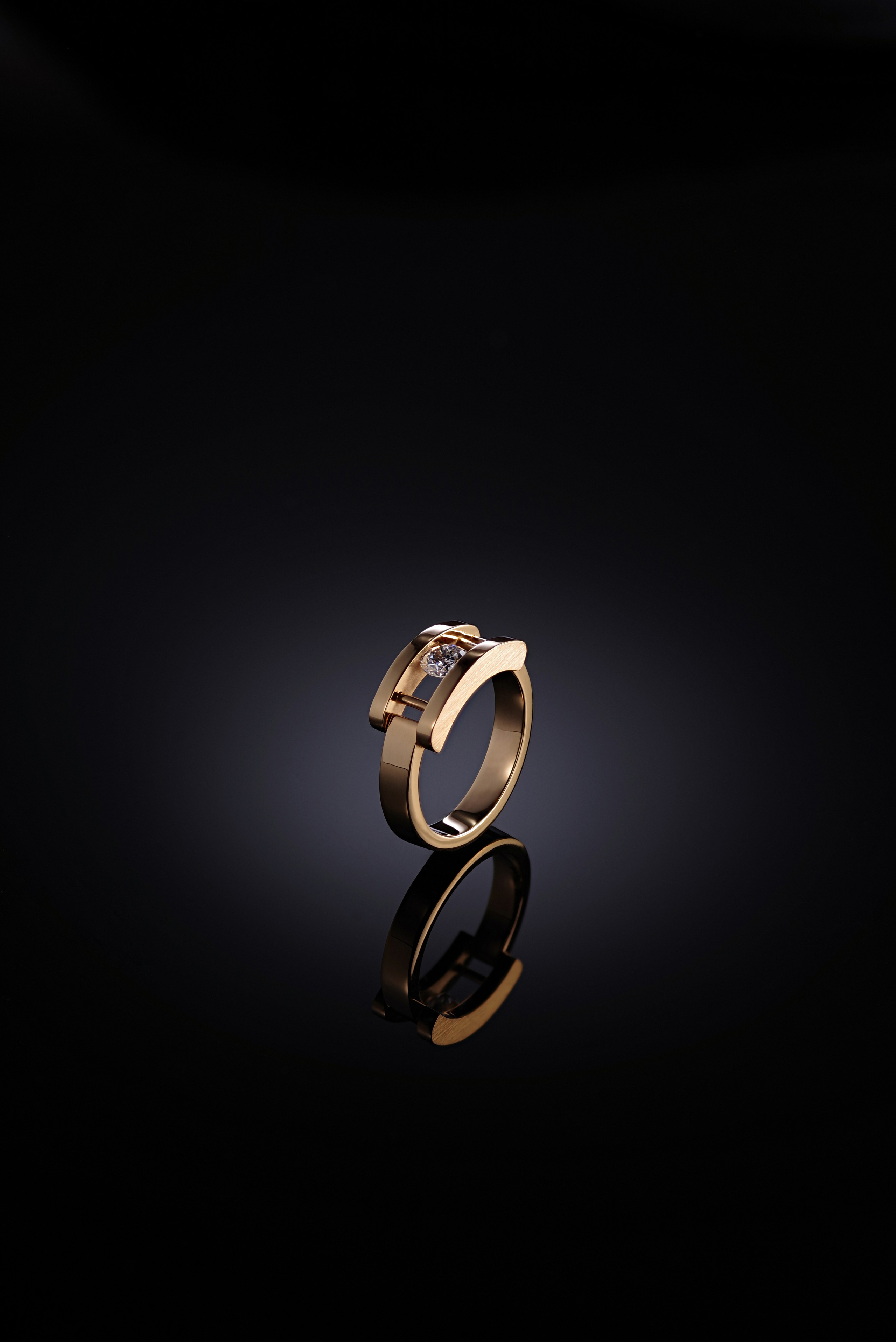 Кольцо с бриллиантом на чёрной зеркальной поверхности