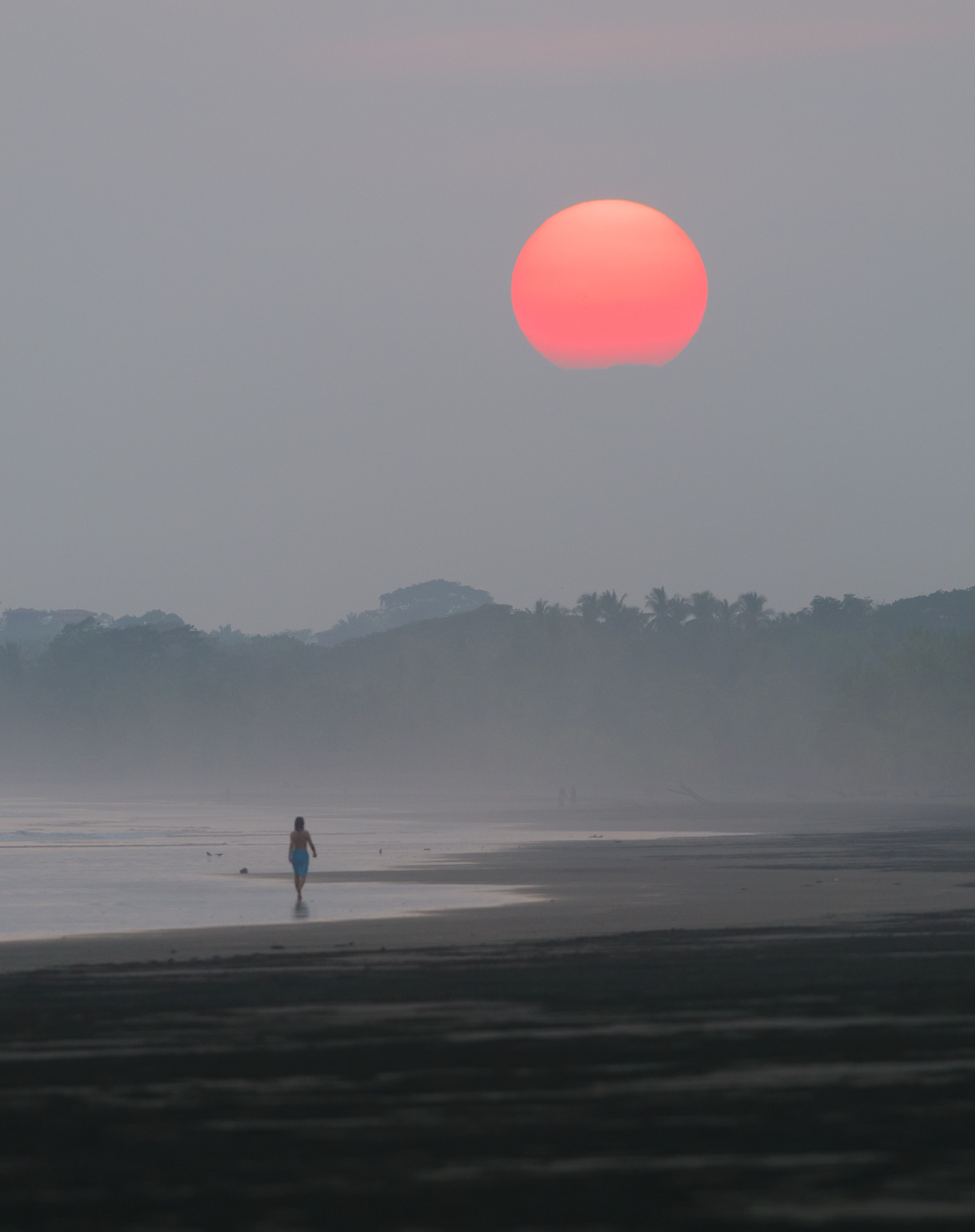 Коста-Рика, вечер, серость, никакого заката, мы уже возвращались по пляжу домой. И вдруг, обернувшись, я увидел эту прекрасную картину: огромный диск красного солнца, на мгновение вынырнувшего из серой мглы и девушку, идущую по пляжу