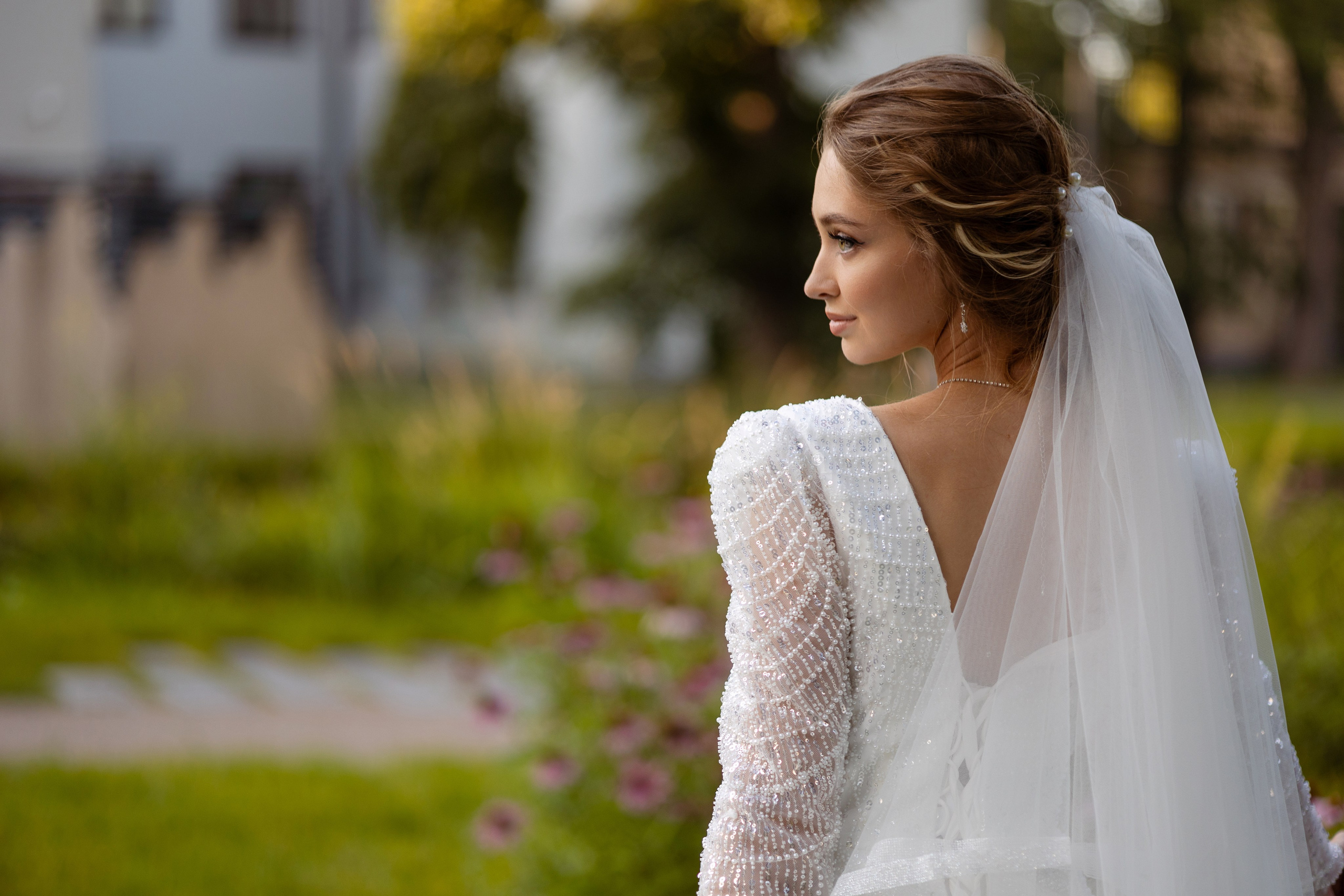 Невеста в профиль на фоне зеленых насаждений.