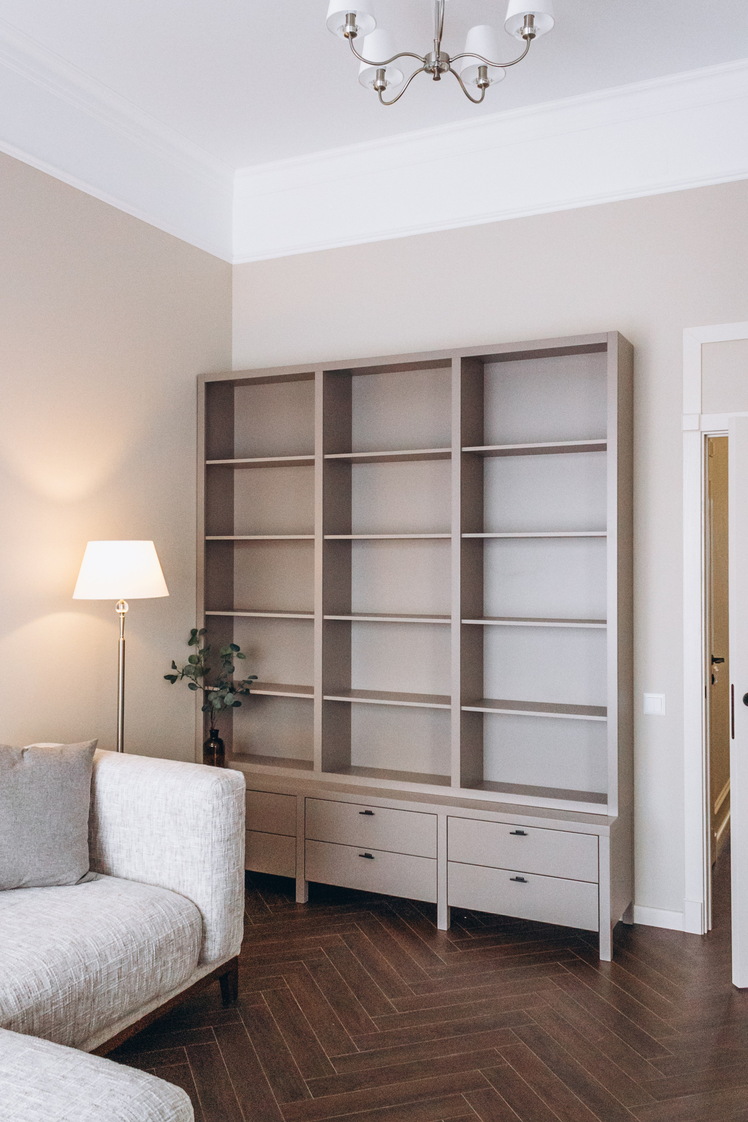 уютная гостиная с большим диваном и серым шкафом для книг