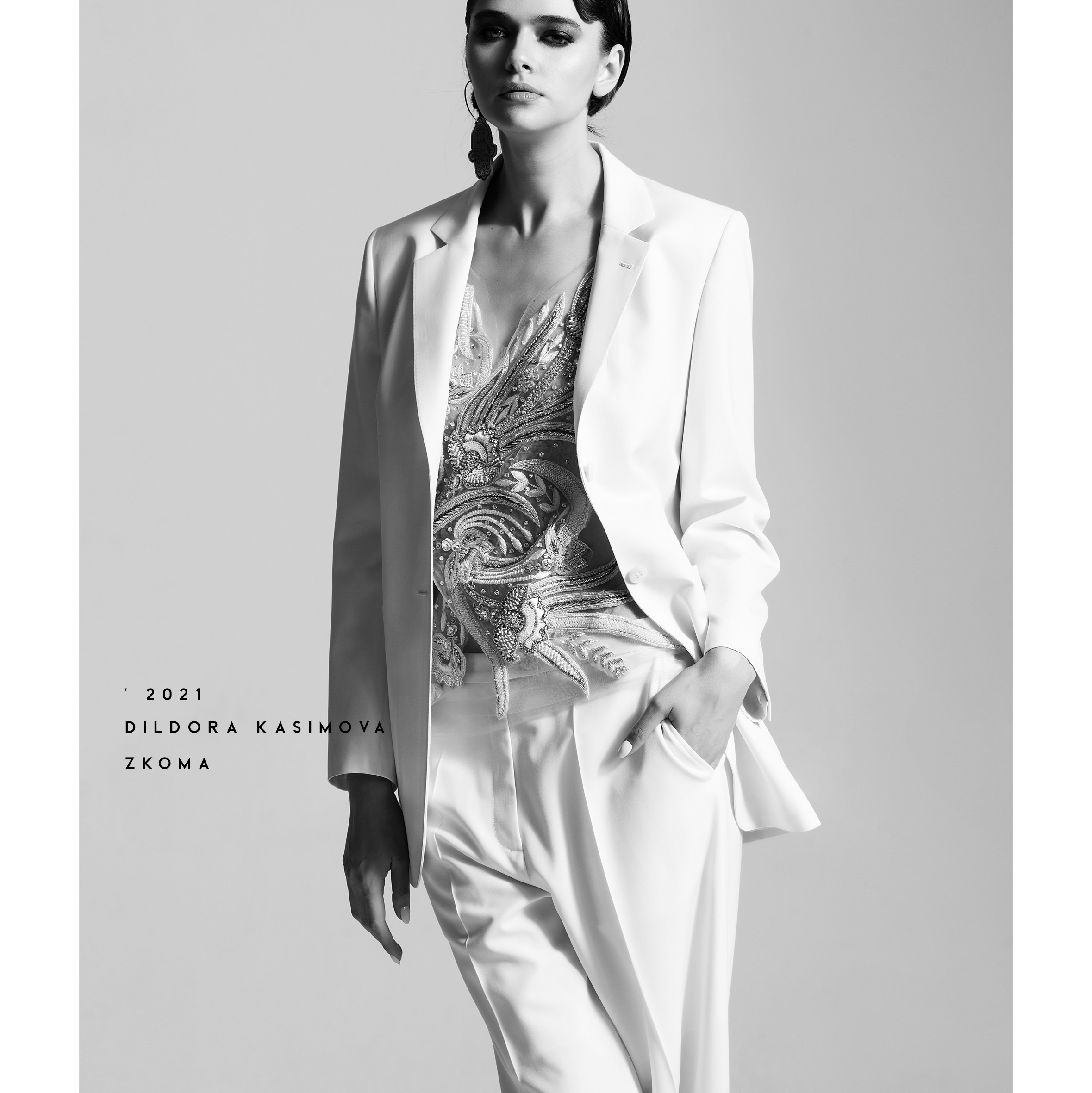 Fashion-портрет в студии: модель в белом брючном костюме и расшитом топе, чёрно-белая съёмка.