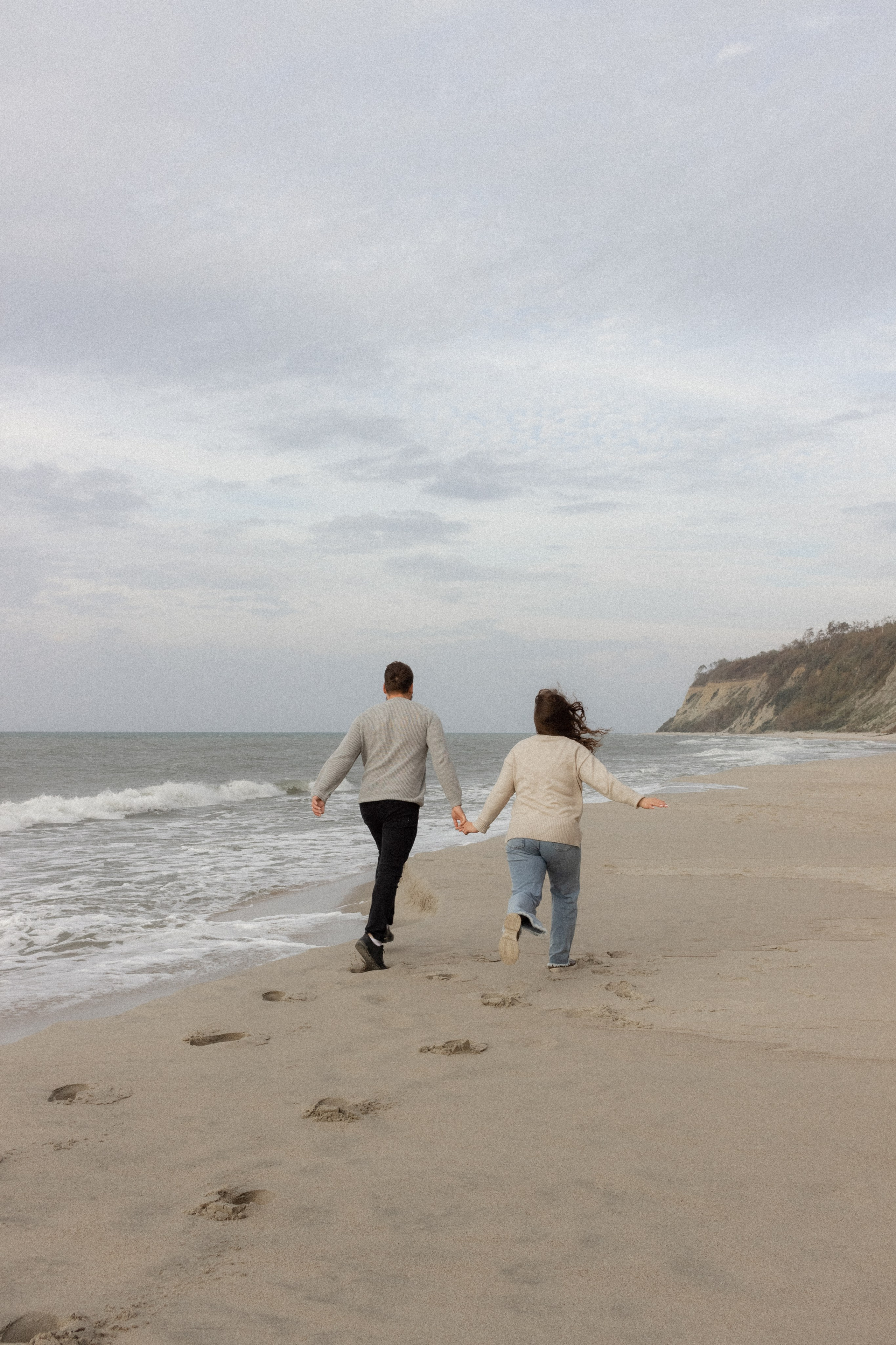 Влюбленная пара бежит по берегу моря 