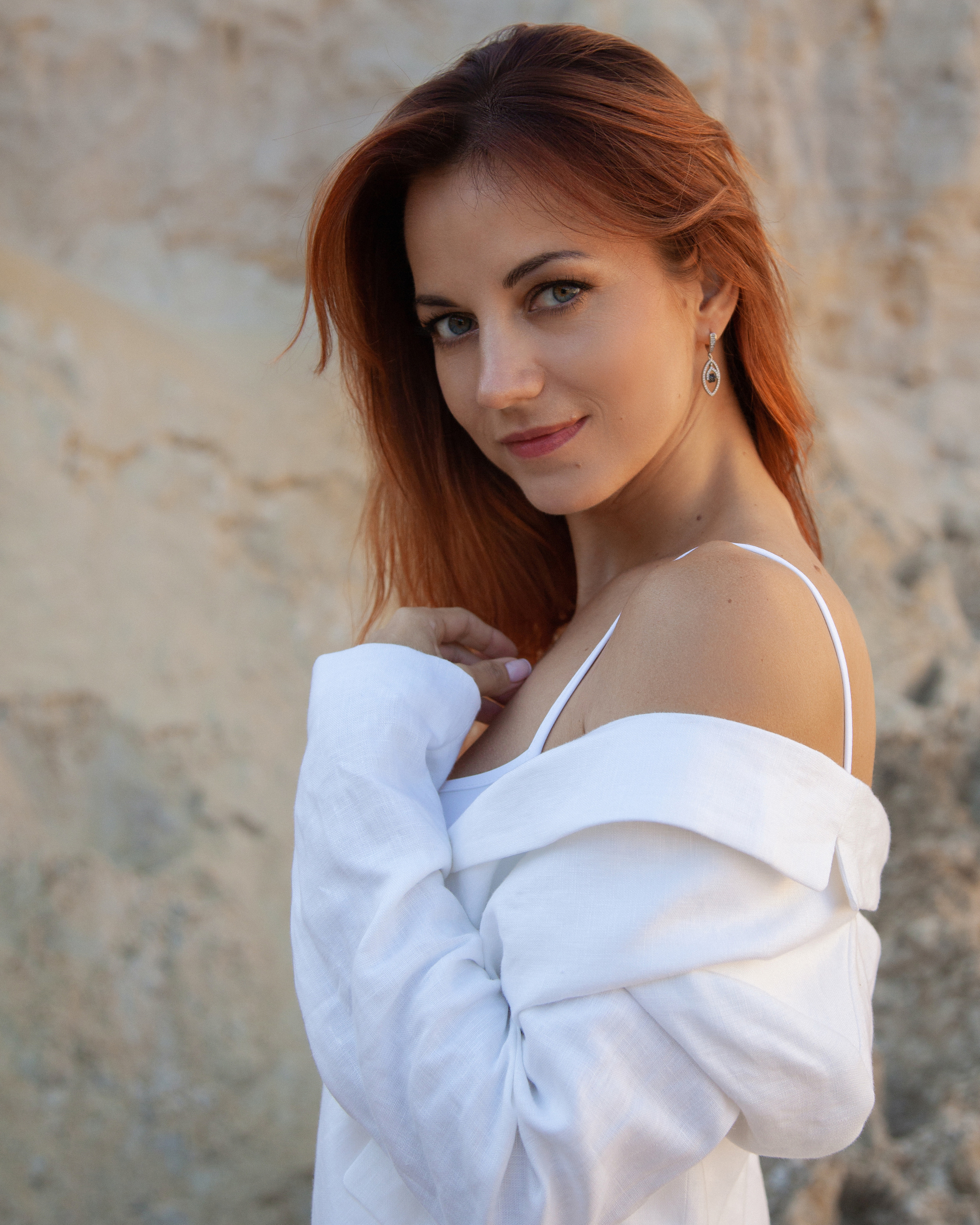 Рыжеволосая девушка позирует на карьере в Подмосковье в белом пиджаке