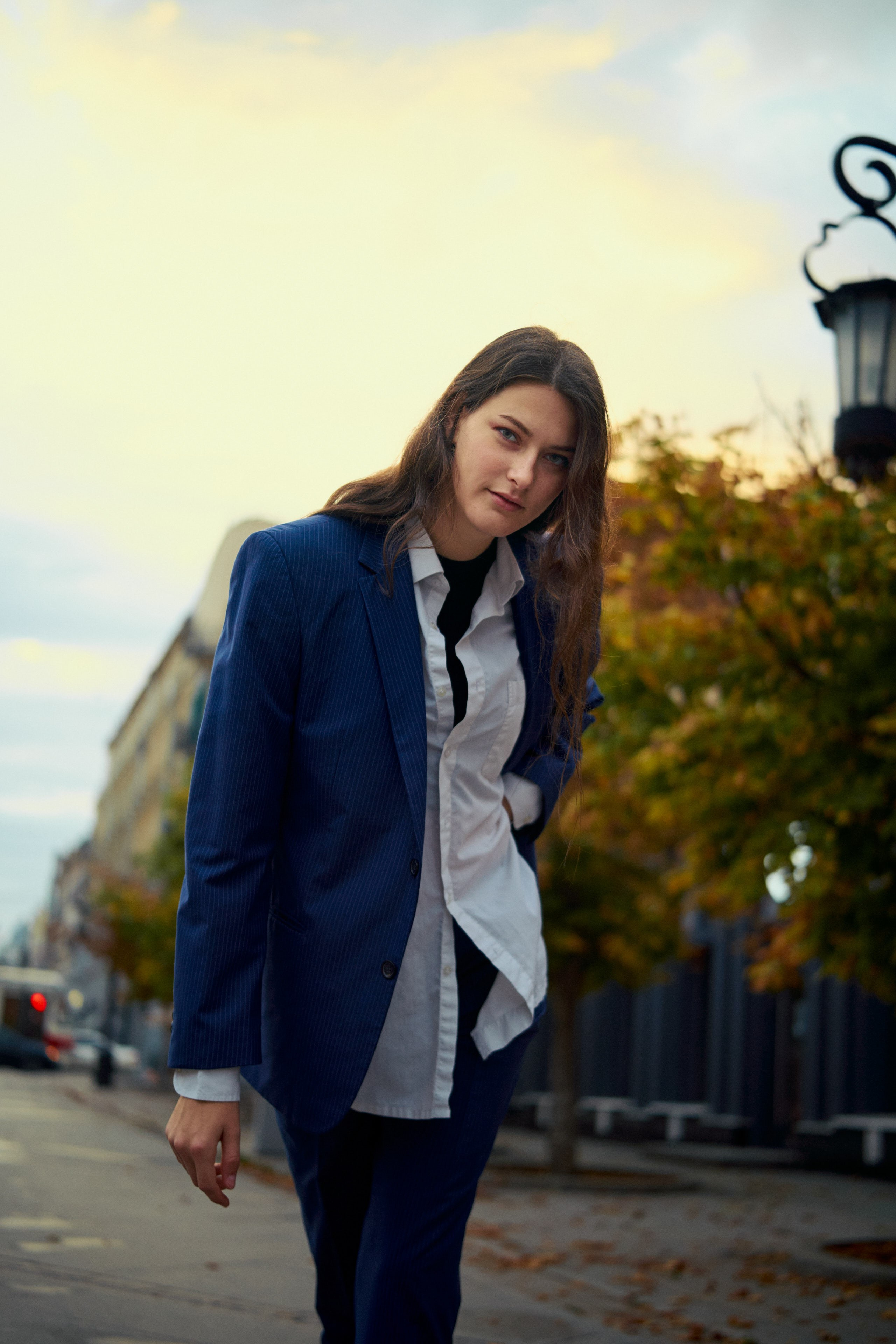 Девушка в классическом пиджаке и рубашке с легким ветром в волосах, создаёт динамичный городской образ