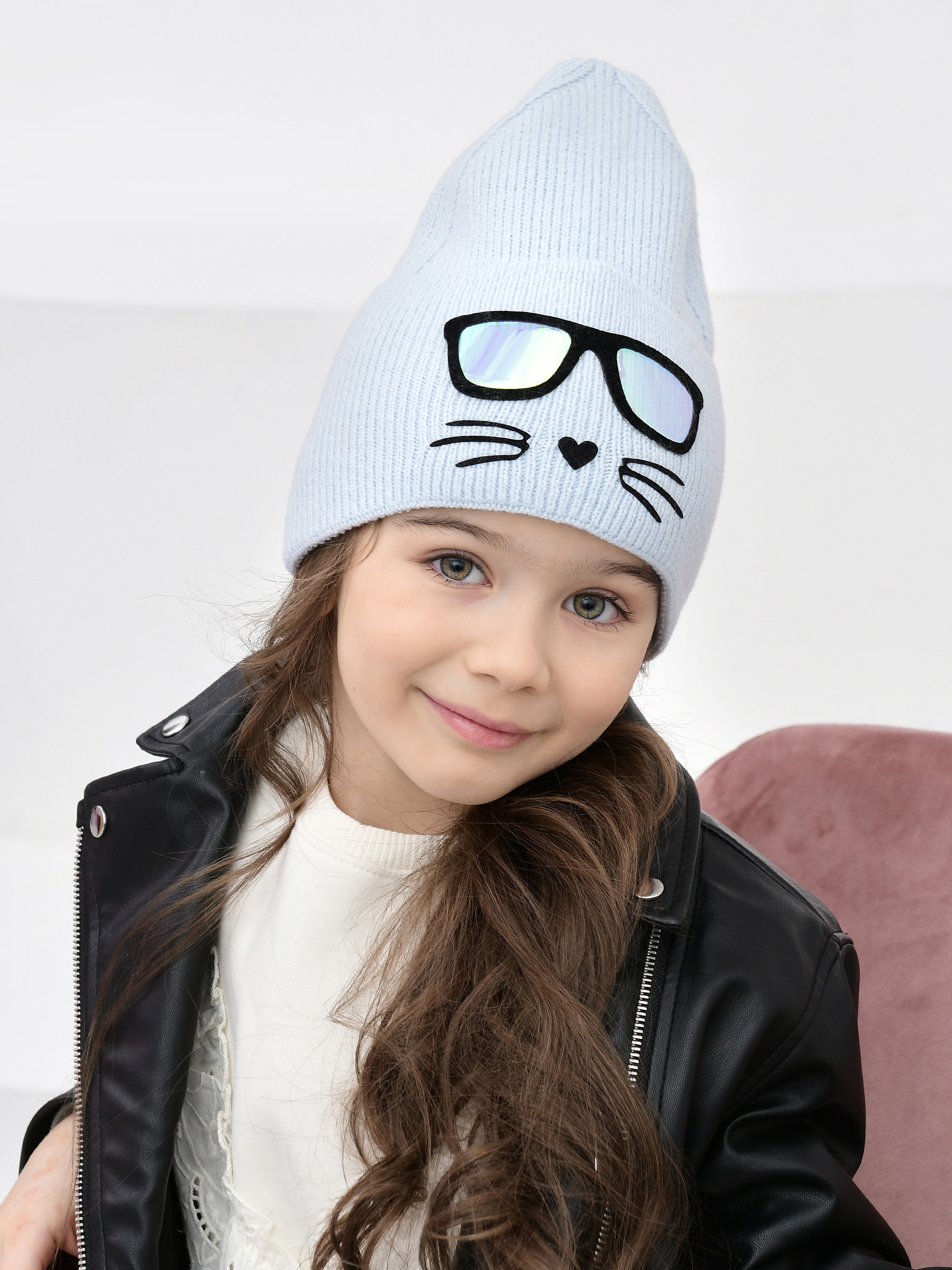 Голубая детская шапка на модели в интерьерной студии.