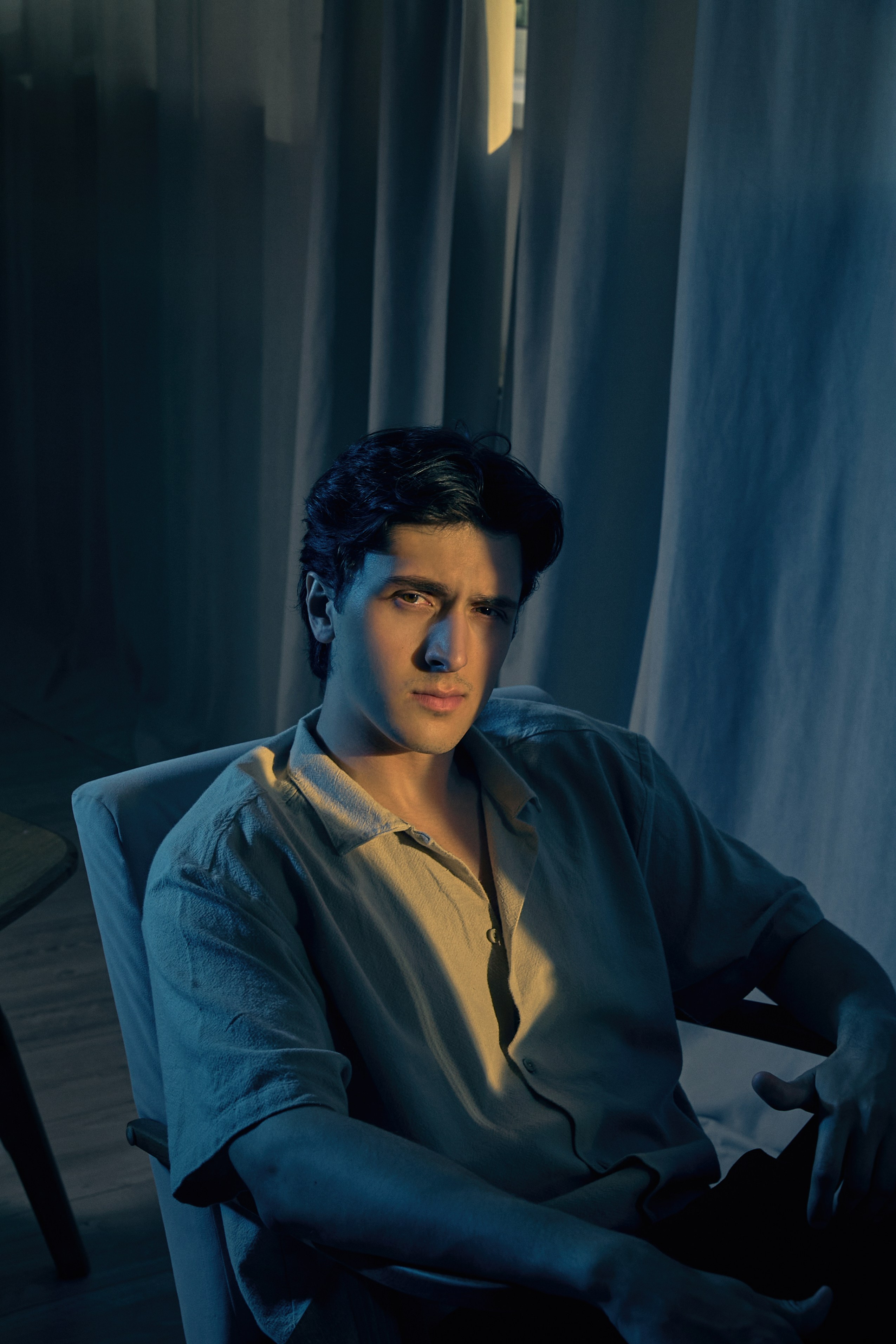 Мужской портрет в кресле с жёлтой полоской света на лице и синей подсветкой