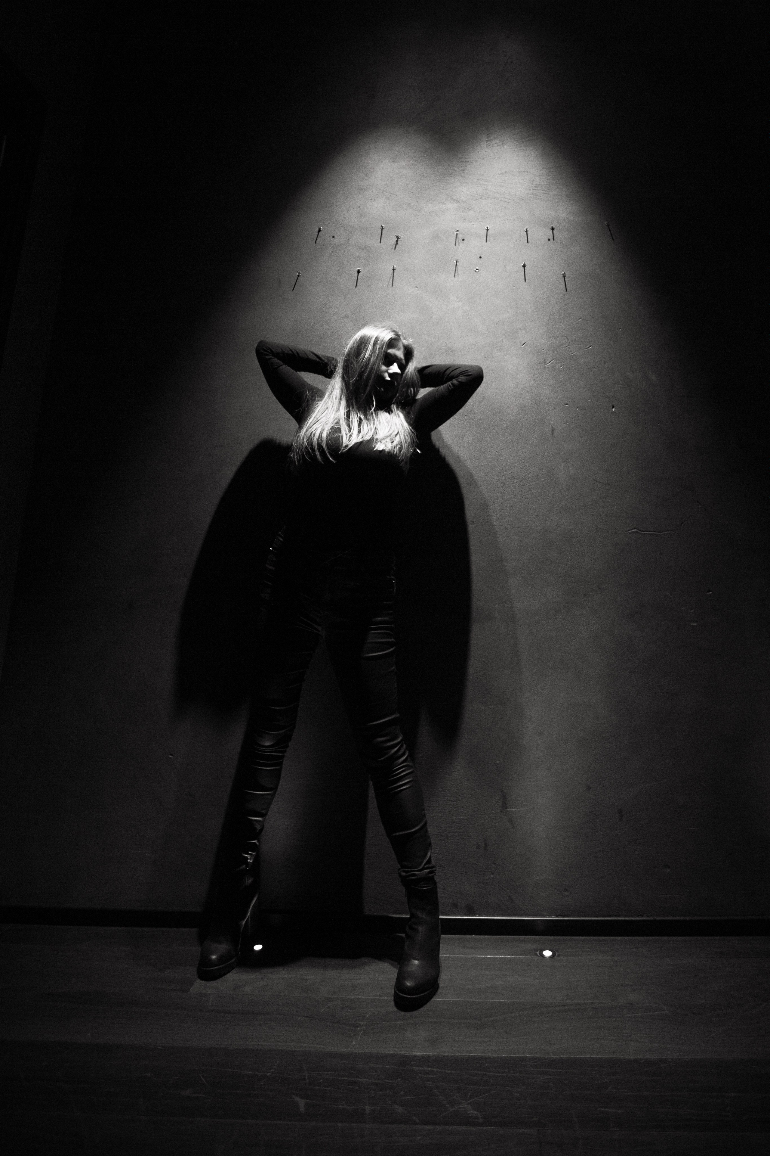 индивидуальная фотосессия в студии где девушка стоит у стены с освещением тень на стене в виде крыльев