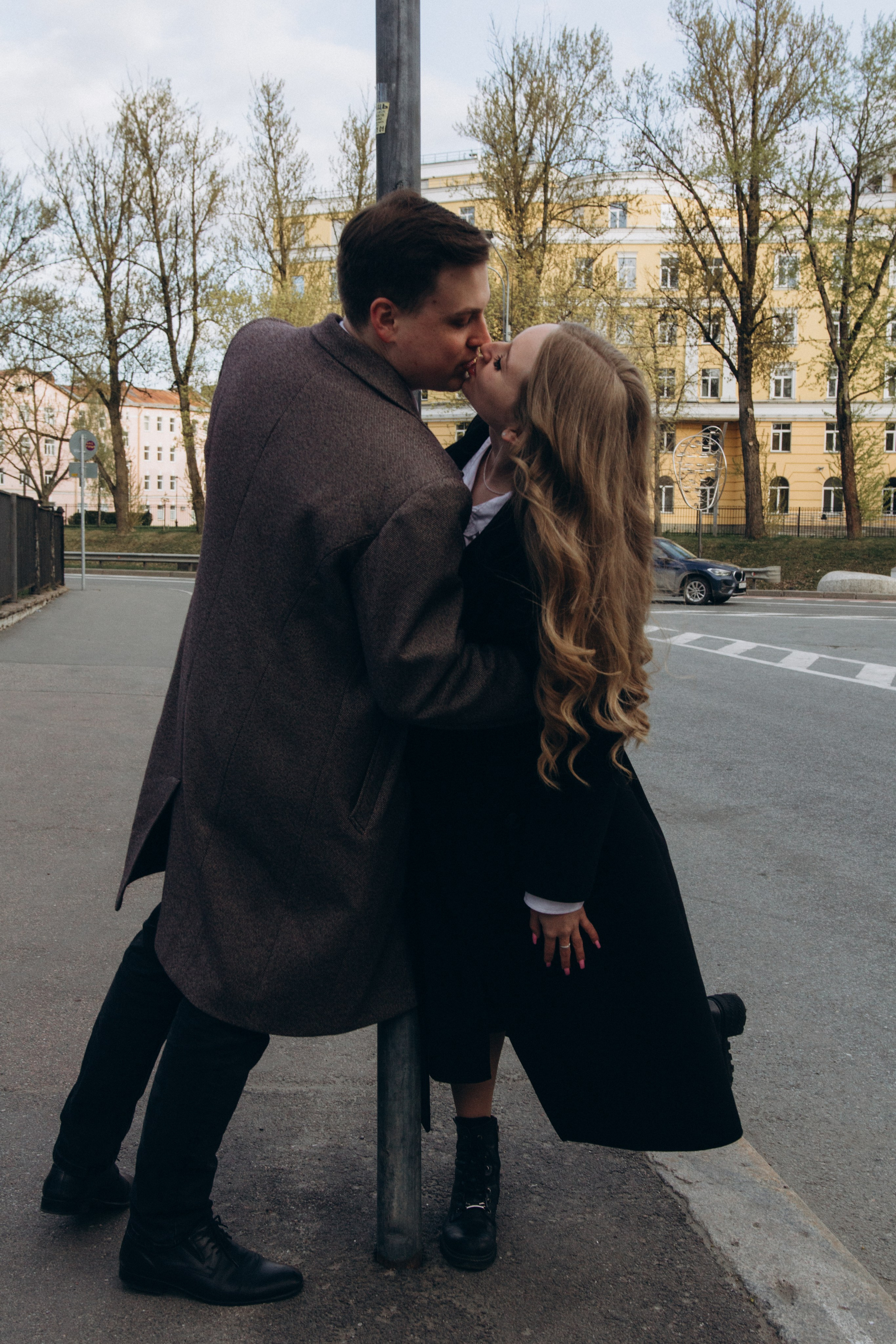 молодая пара стоит целуется у столба в городе