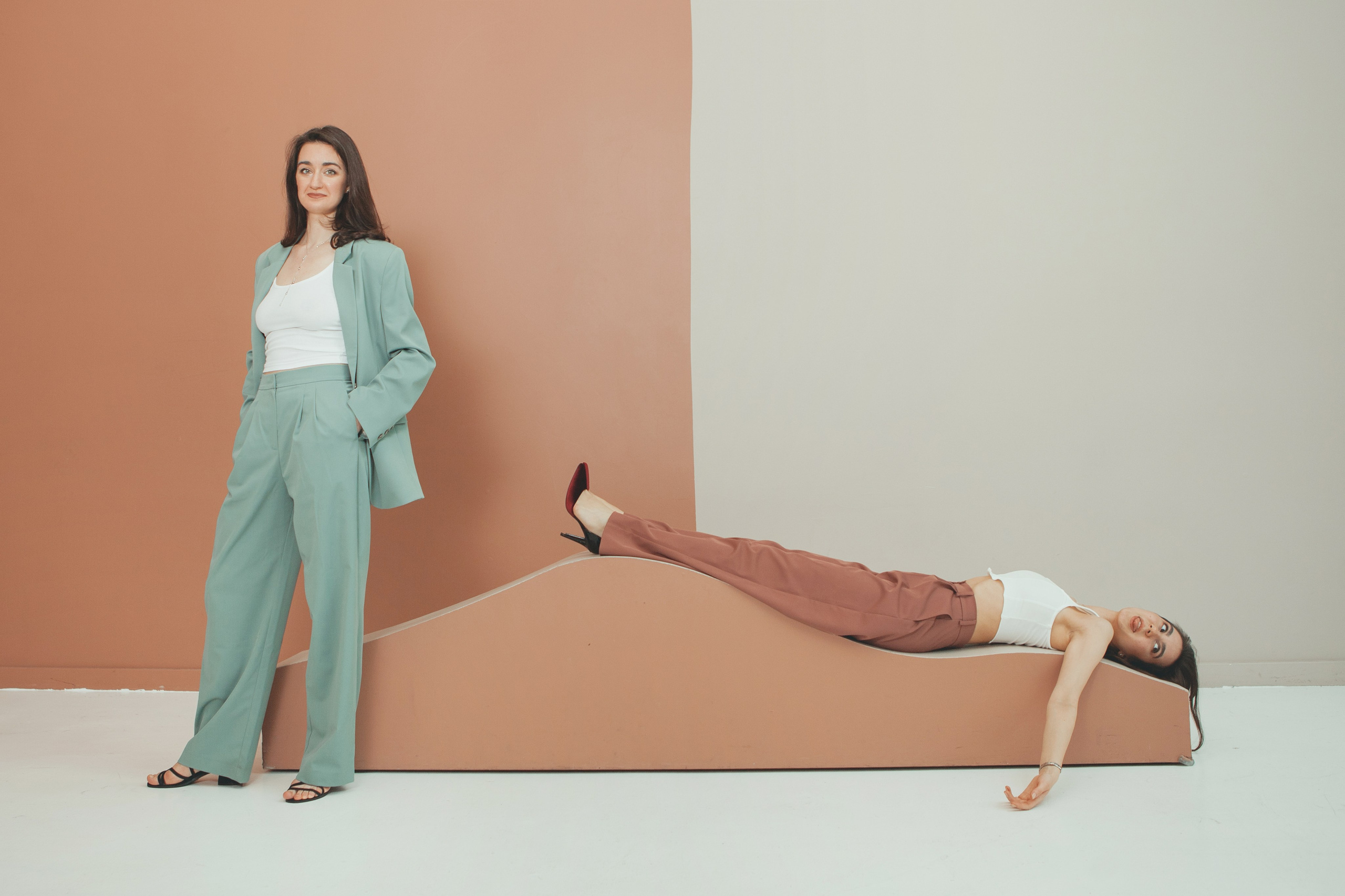 две красивых девушки позируют на фото: одна лежит, вторая стоит