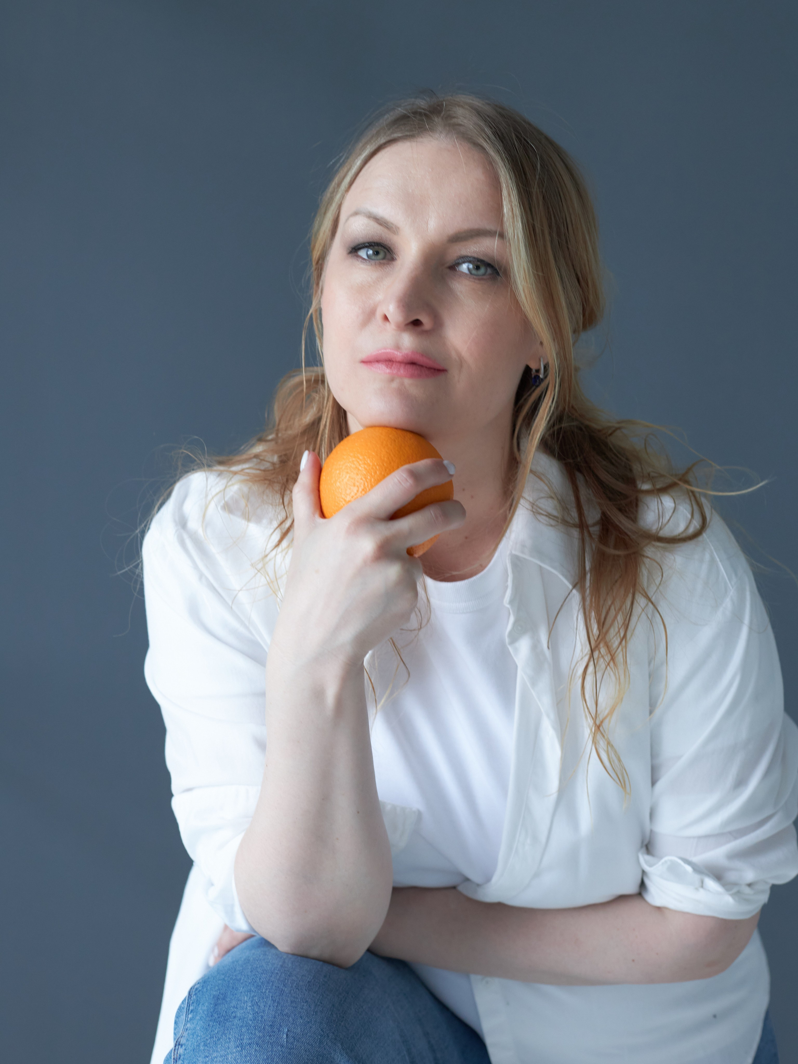 Девушка в белой футболке с апельсином в руках