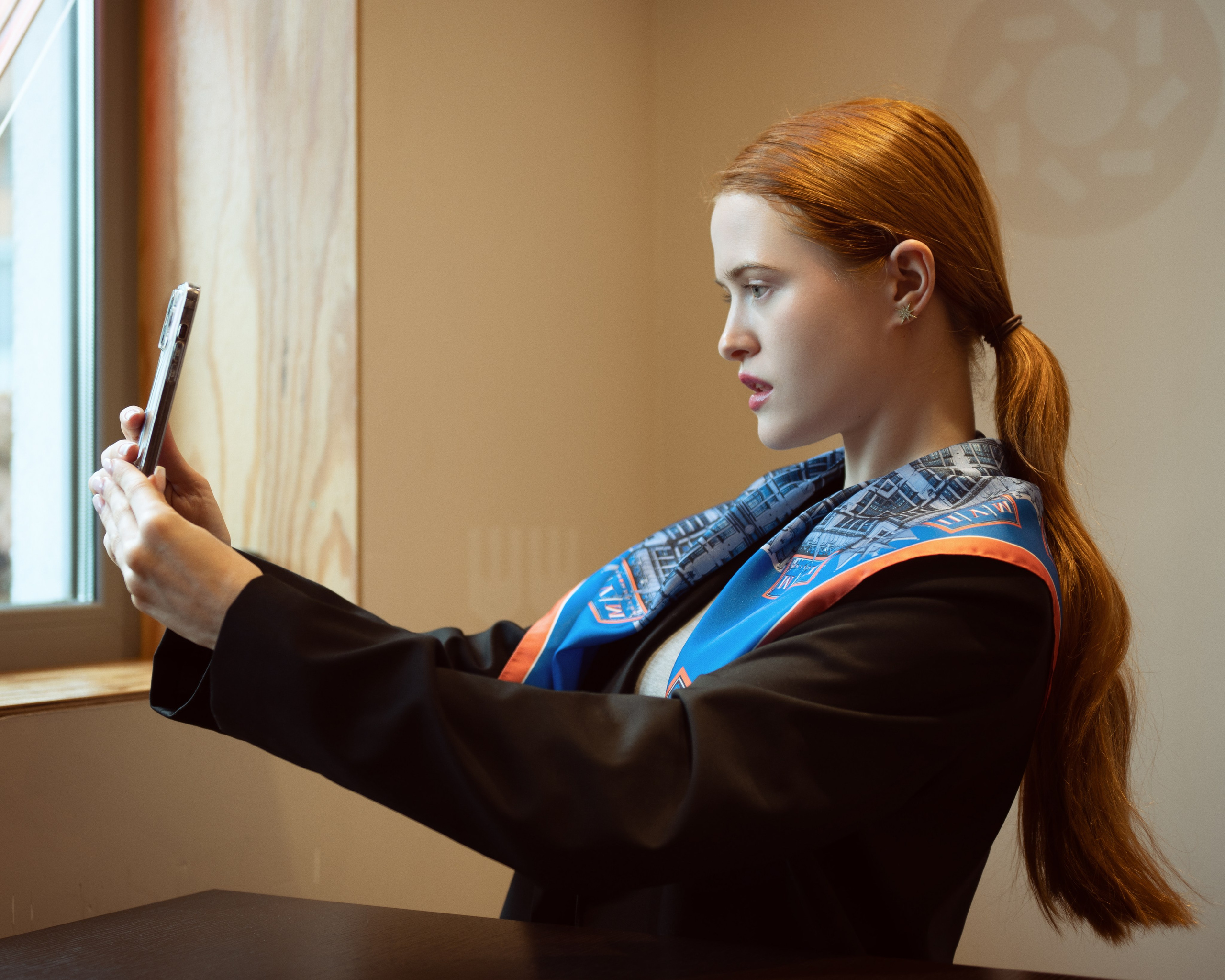 Красивая рыжеволосая девушка делает сэлфи. На ней черный пиджак, а на плечах яркий синий платок.