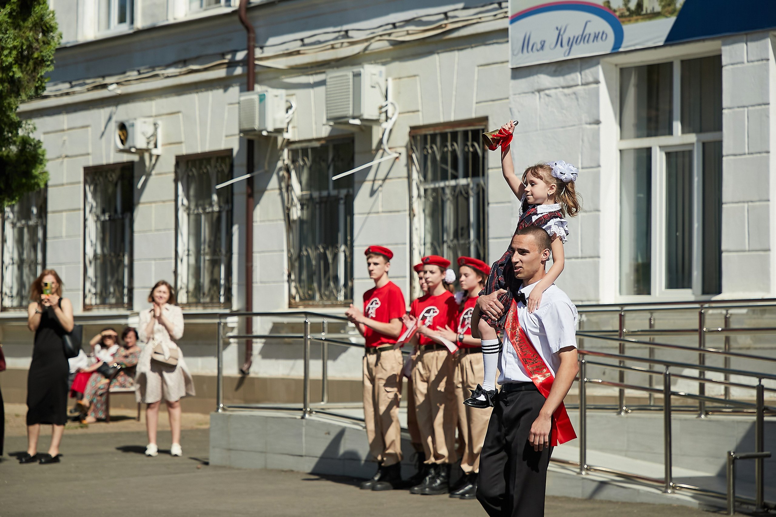 последний звонок Краснодар, выпускник несет первоклашку на последнем звонке Краснодар