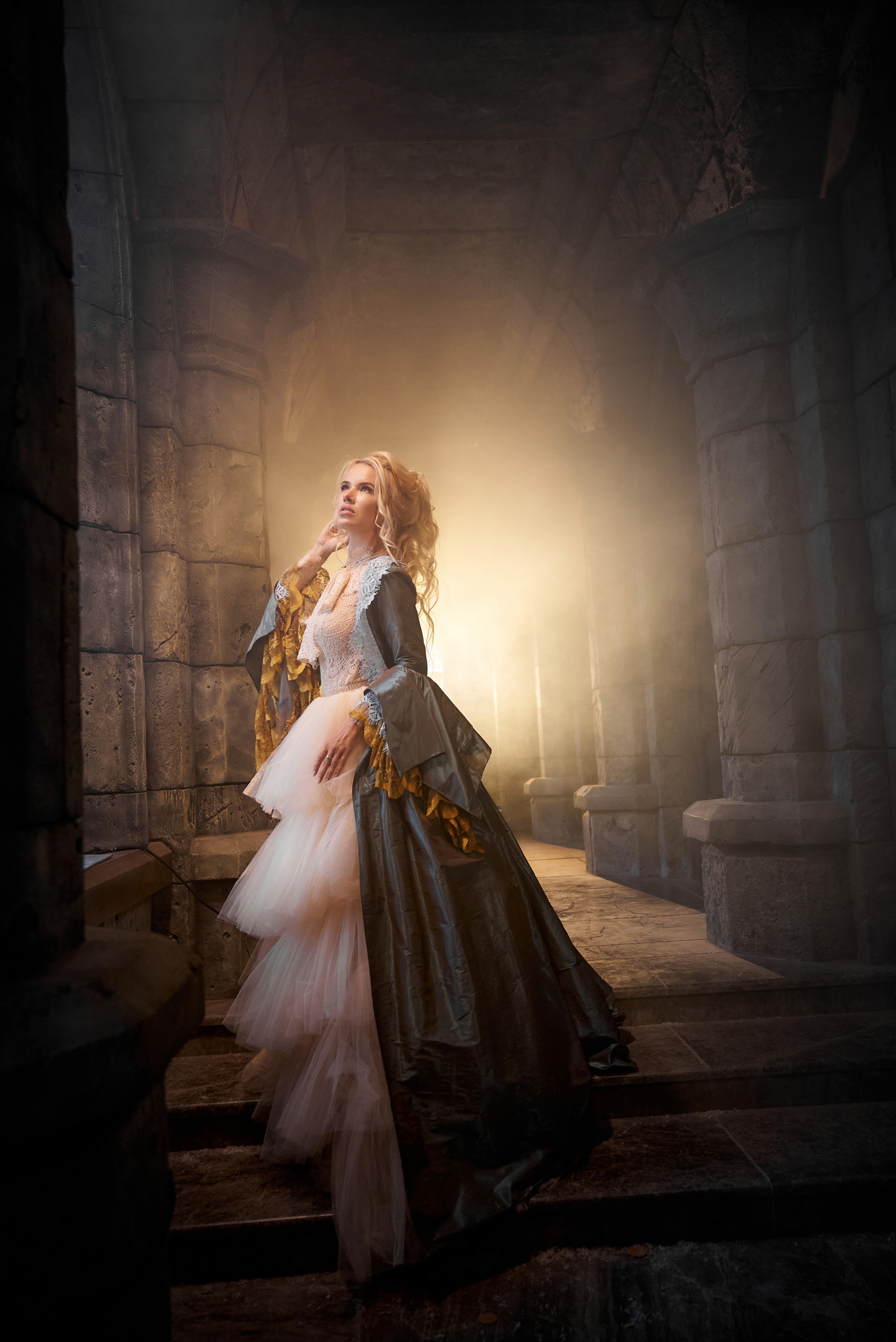 Модель в полумраке арочного прохода замка Гарибальди, окружённая тёплым сиянием свечей, создающих готический колорит.