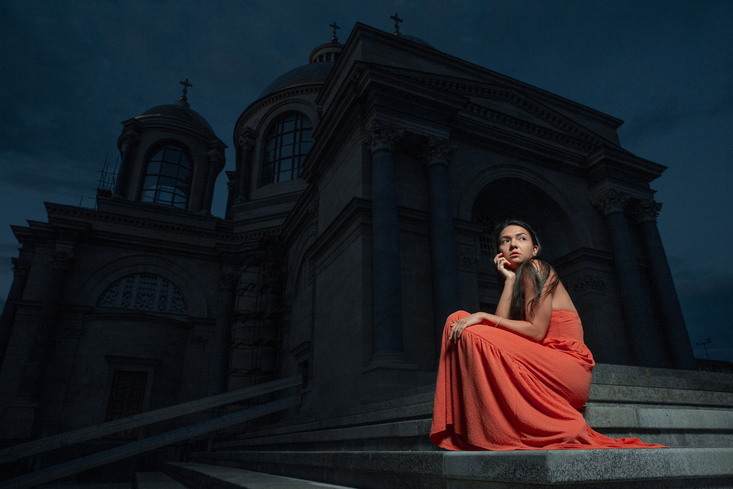 Female portrait in red dress with church behind 