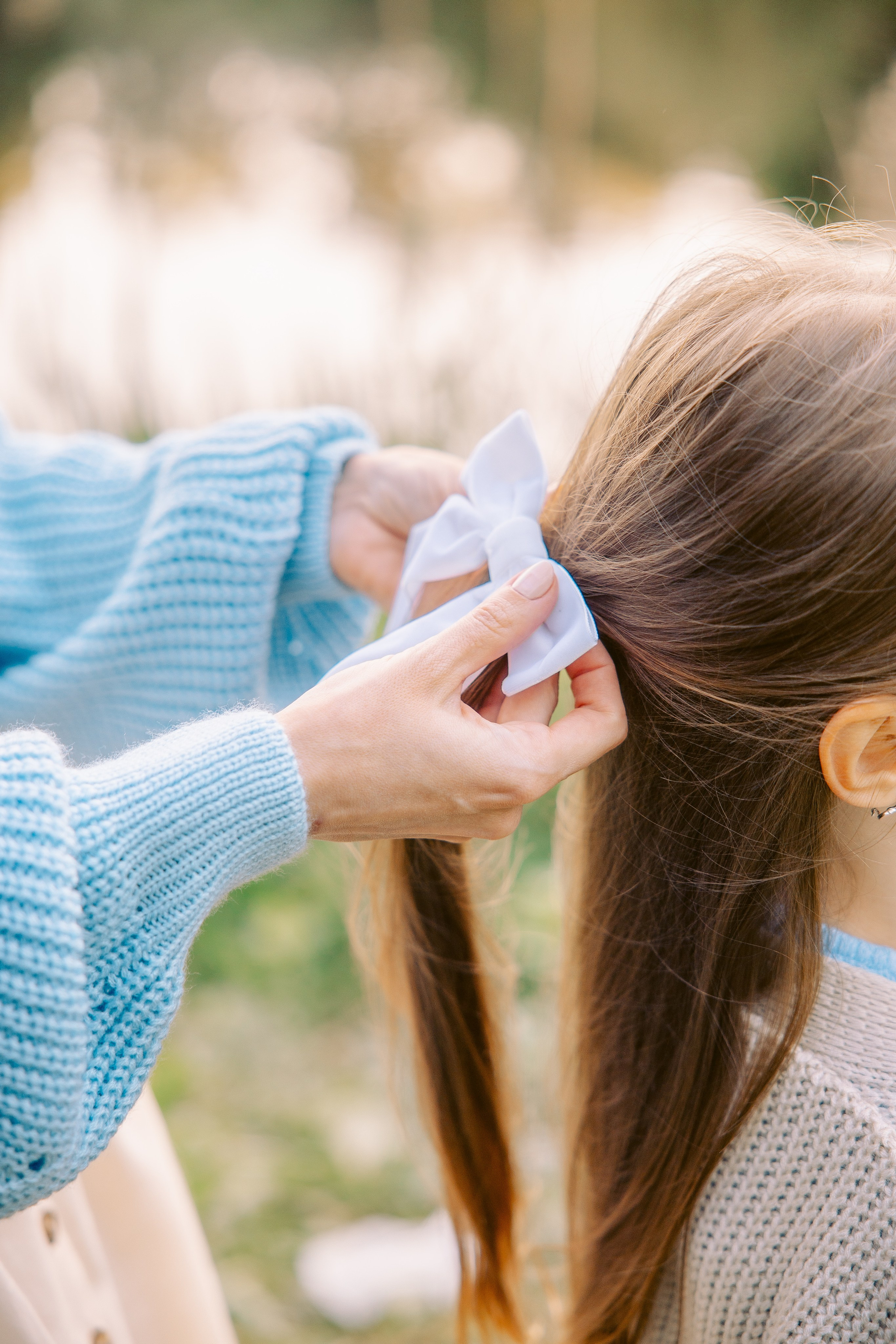 мама поправляет бантик дочке 