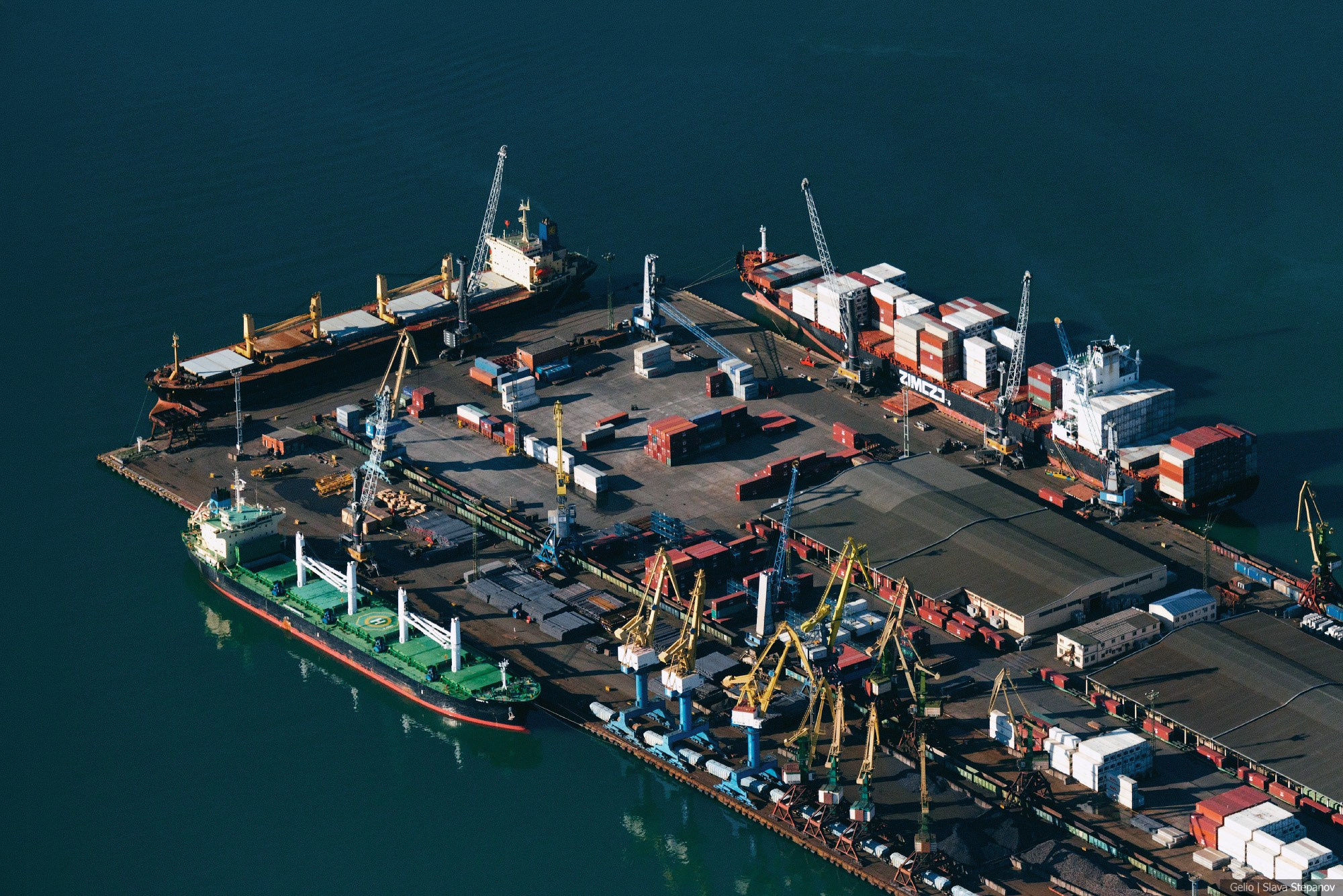 Панорама крупного морского терминала с высоты, погрузка контейнеровозов и балкеров с помощью портальных кранов, портовая логистика, фото Slava Stepanov
