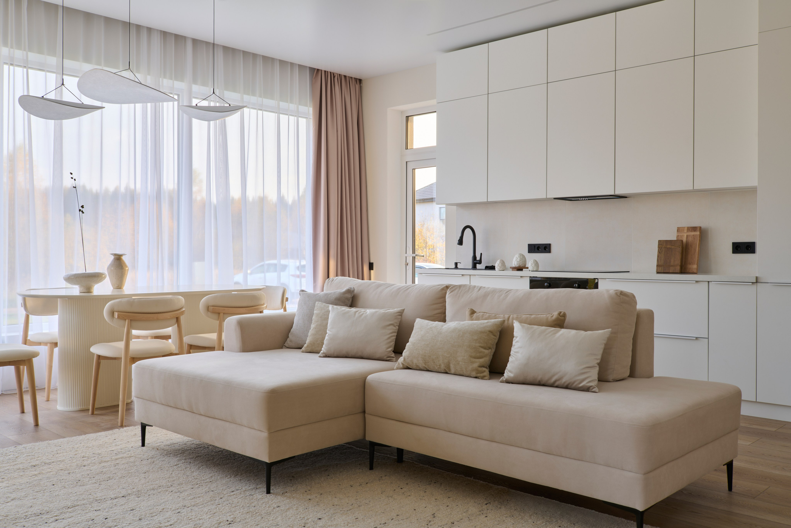 Гостиная: большой диван, кухня на фоне и панорамные шторы
