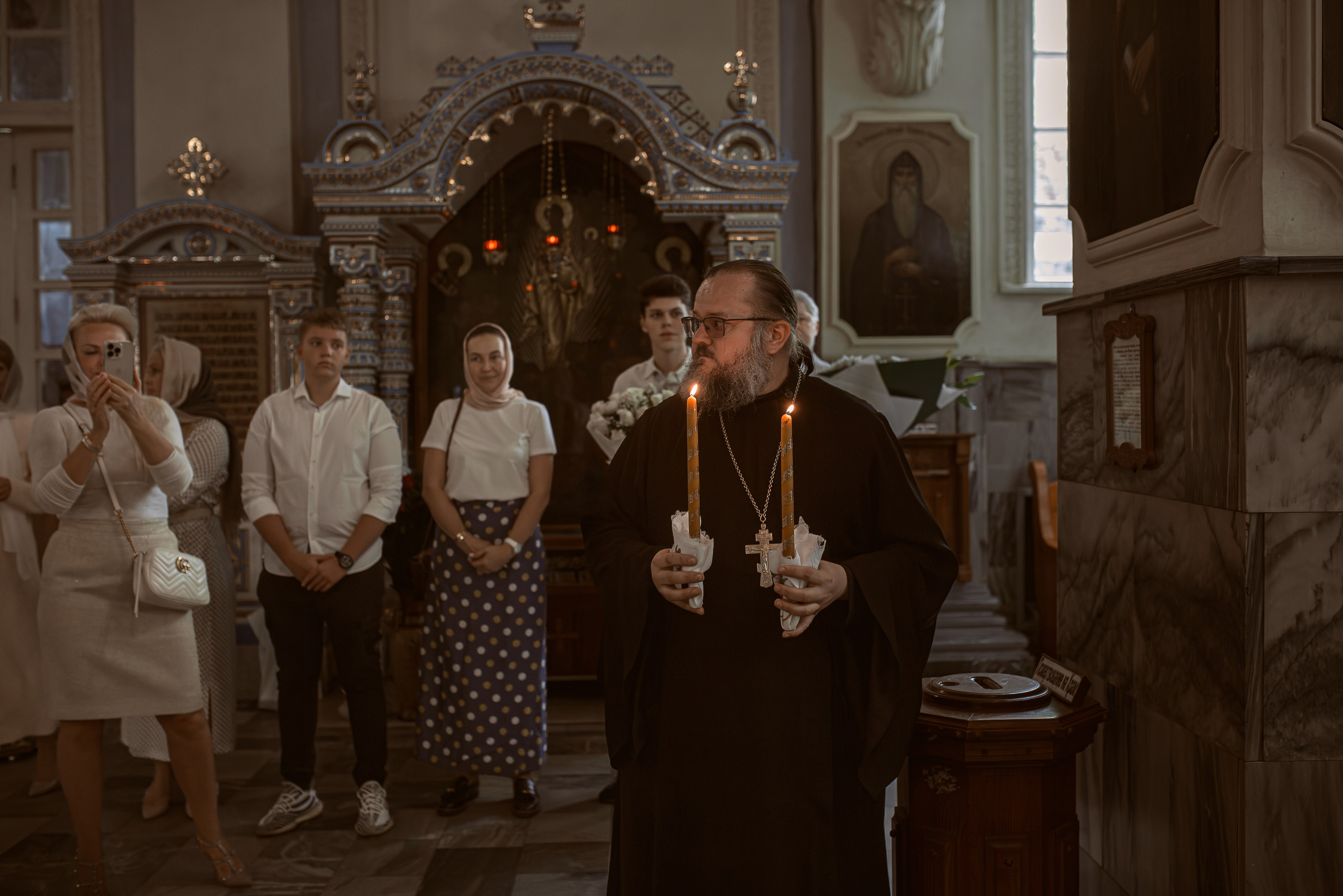 иеромонах Михаил (Столяров) держит свечи перед венчанием в Успенском кафедральном соборе Ташкента