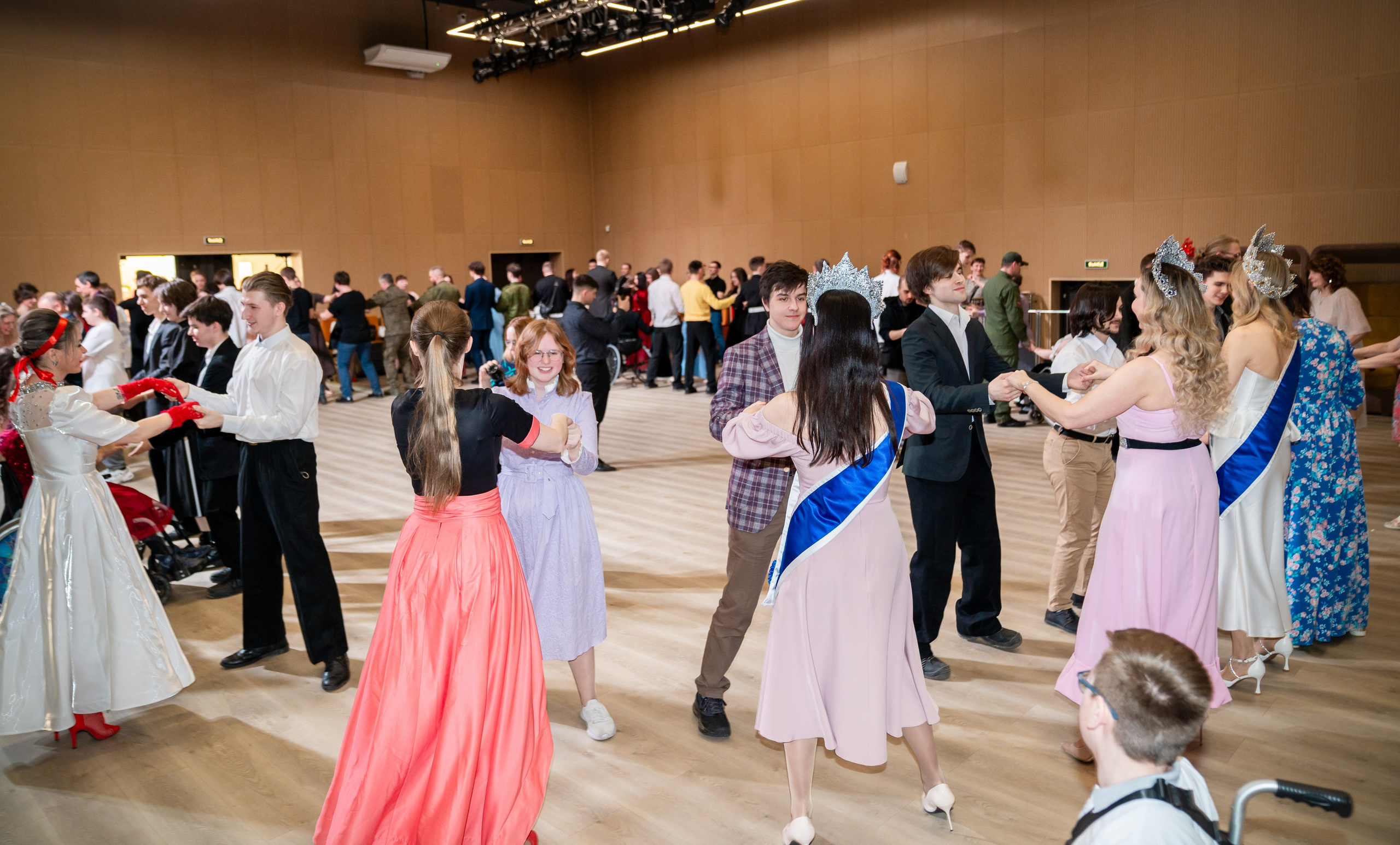 Танцующие пары на инклюзивном балу проекта «Мы все равны». Девушки с лентами «Мисс» и коронами. Фотограф Мальцев Евгений.