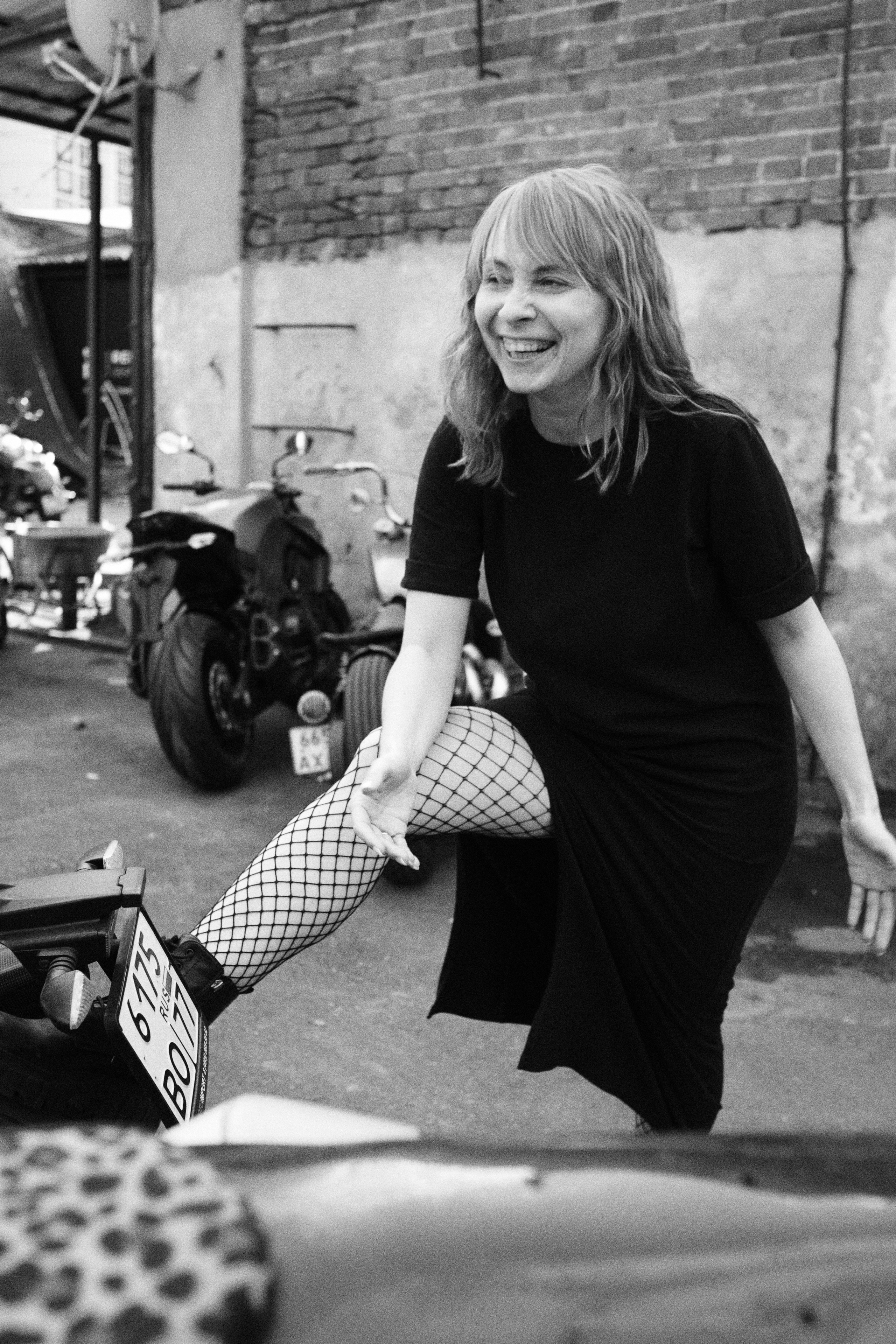 Женщина в черном платье и сетчатых колготах на фоне мотоциклов