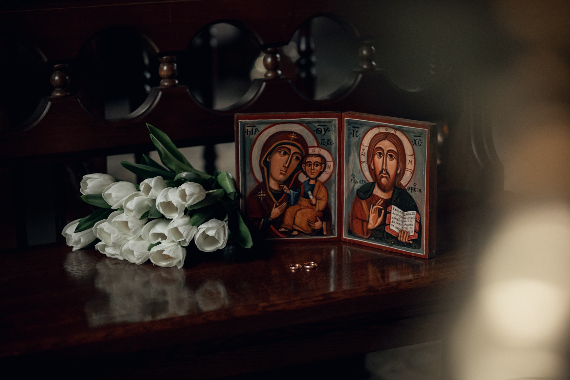венчальные иконы, кольца и тюльпаны лежат на деревянном столике