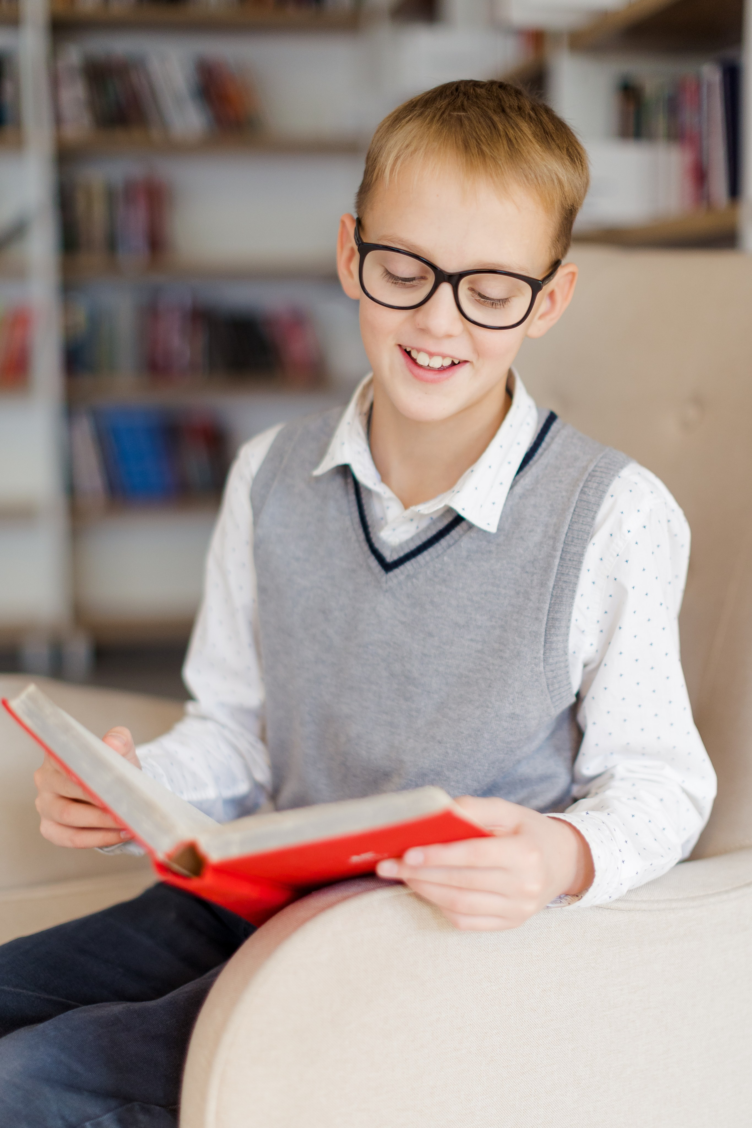 Мальчик сидит с книгой в библиотеке