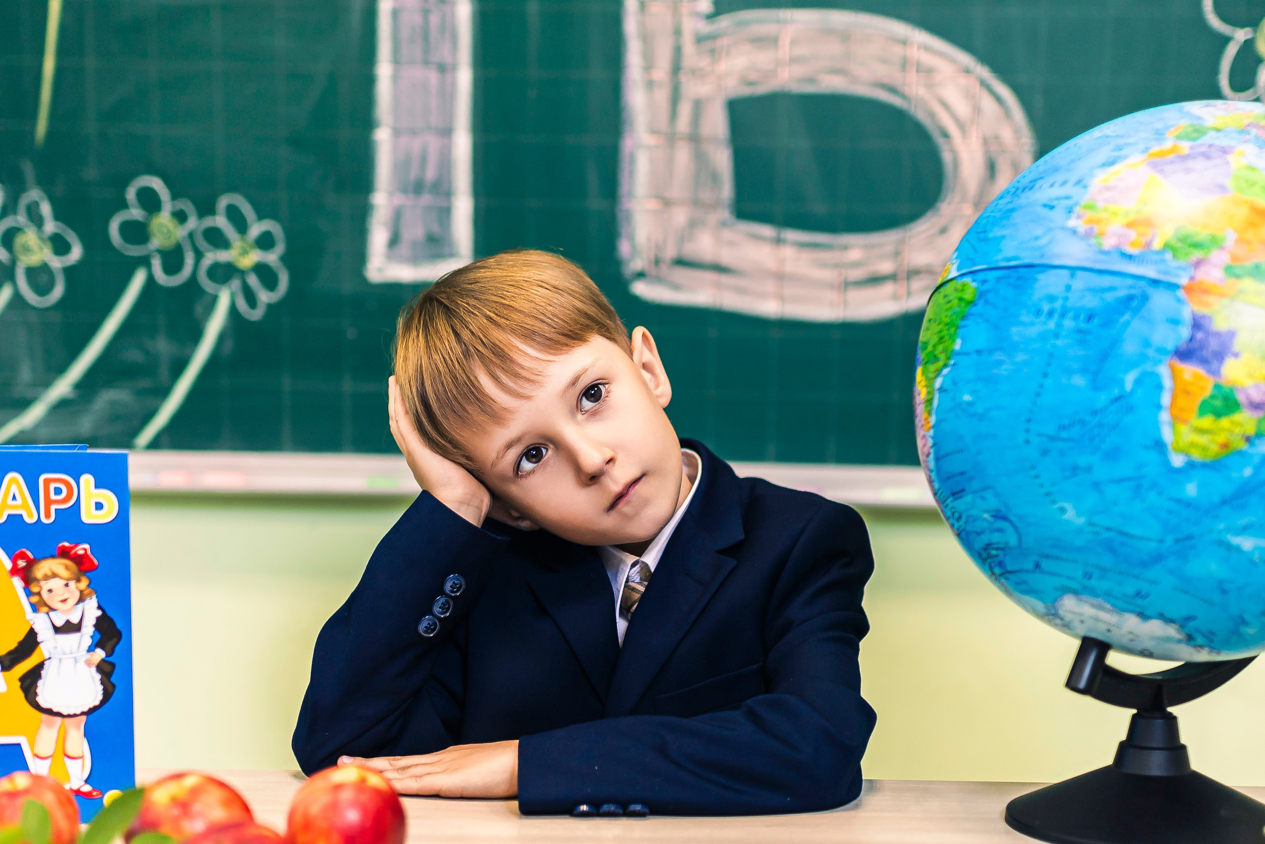 задумчивый школьник сидит за партой 