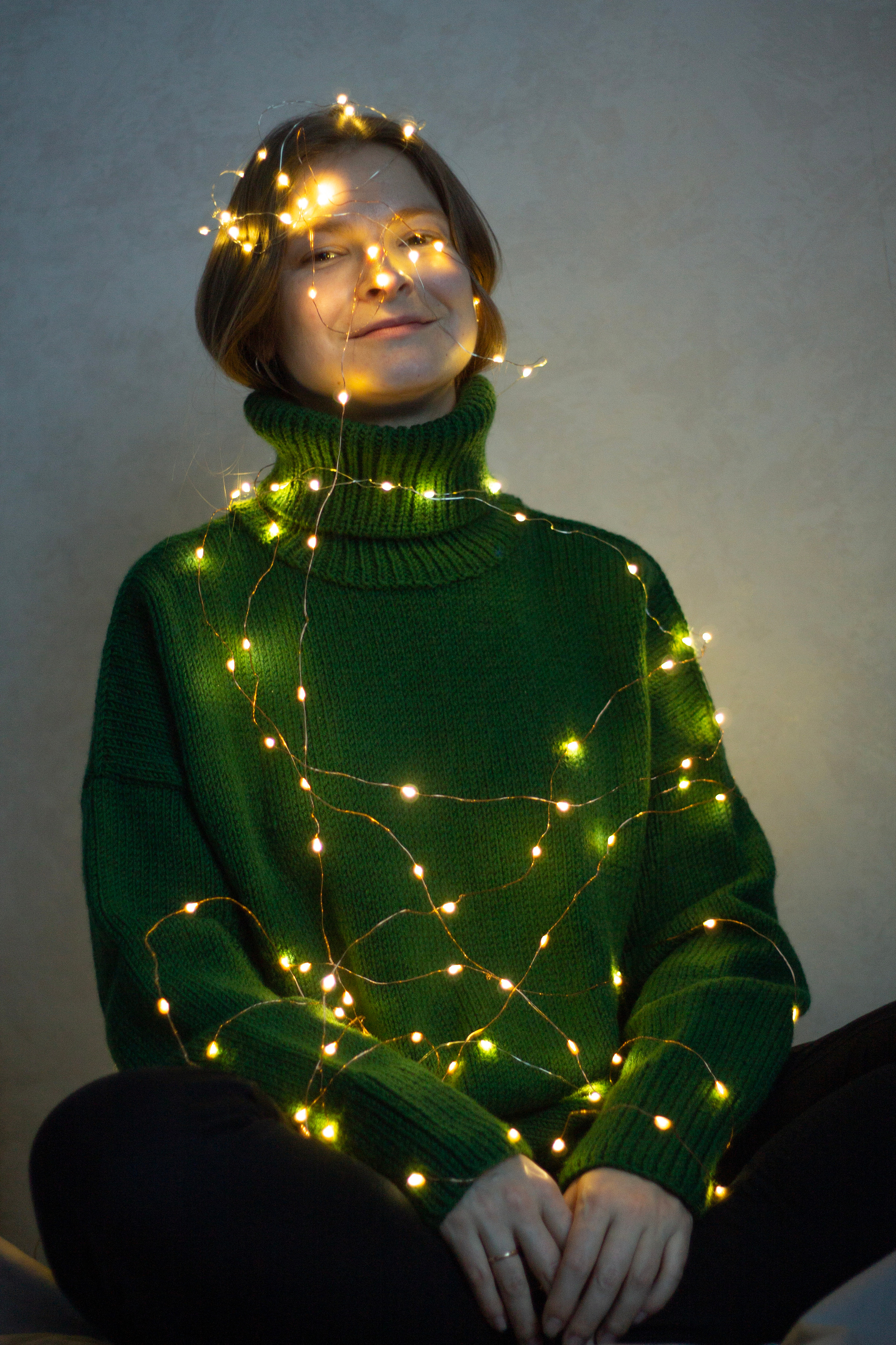 Заказать съемку в бишкеке анна карамурзина фотограф девушка в зеленом свитере сидит обернутая в лампочки