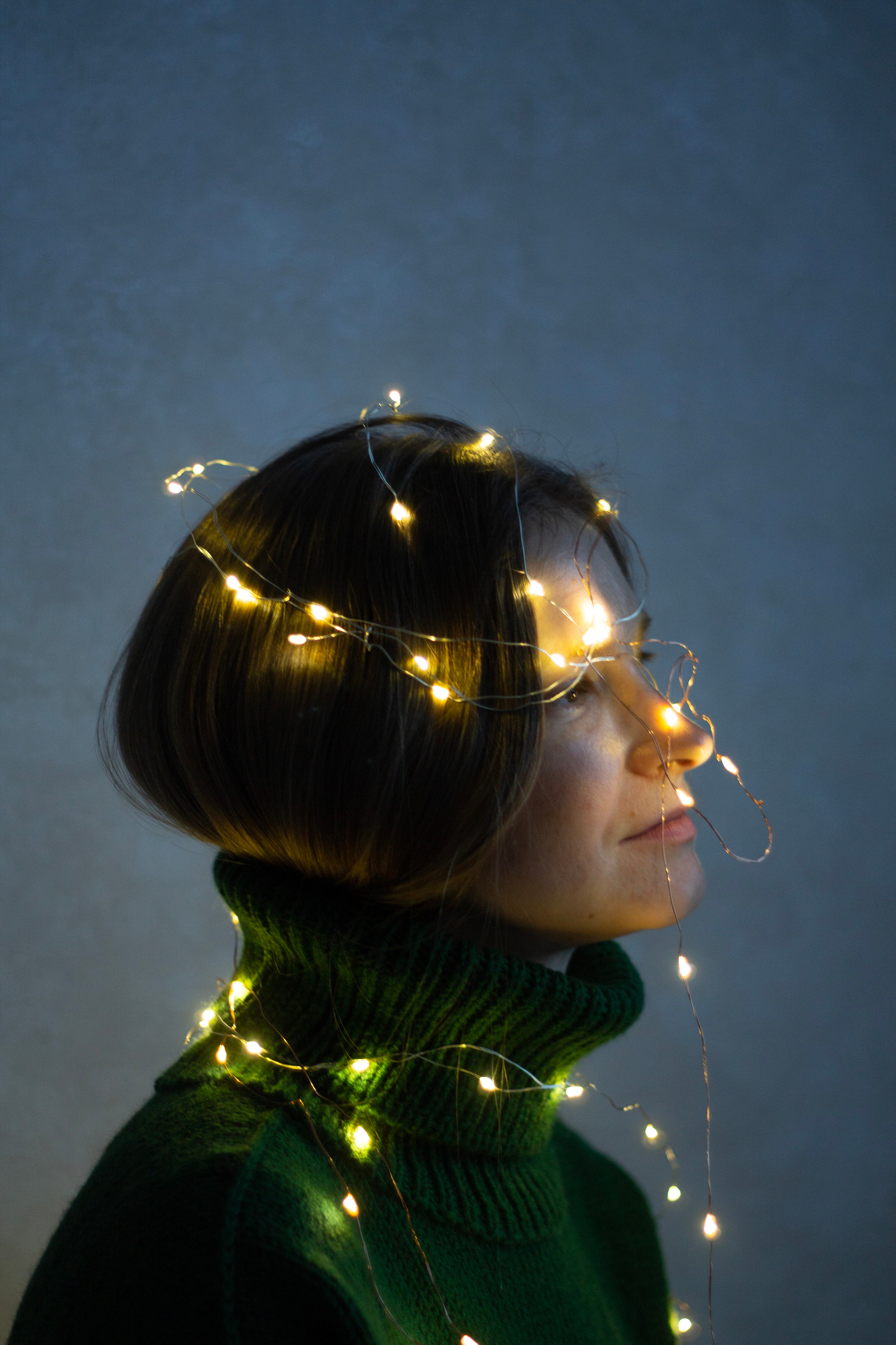 Новогодние фонарики на девушке в зеленом свитере арт портрет