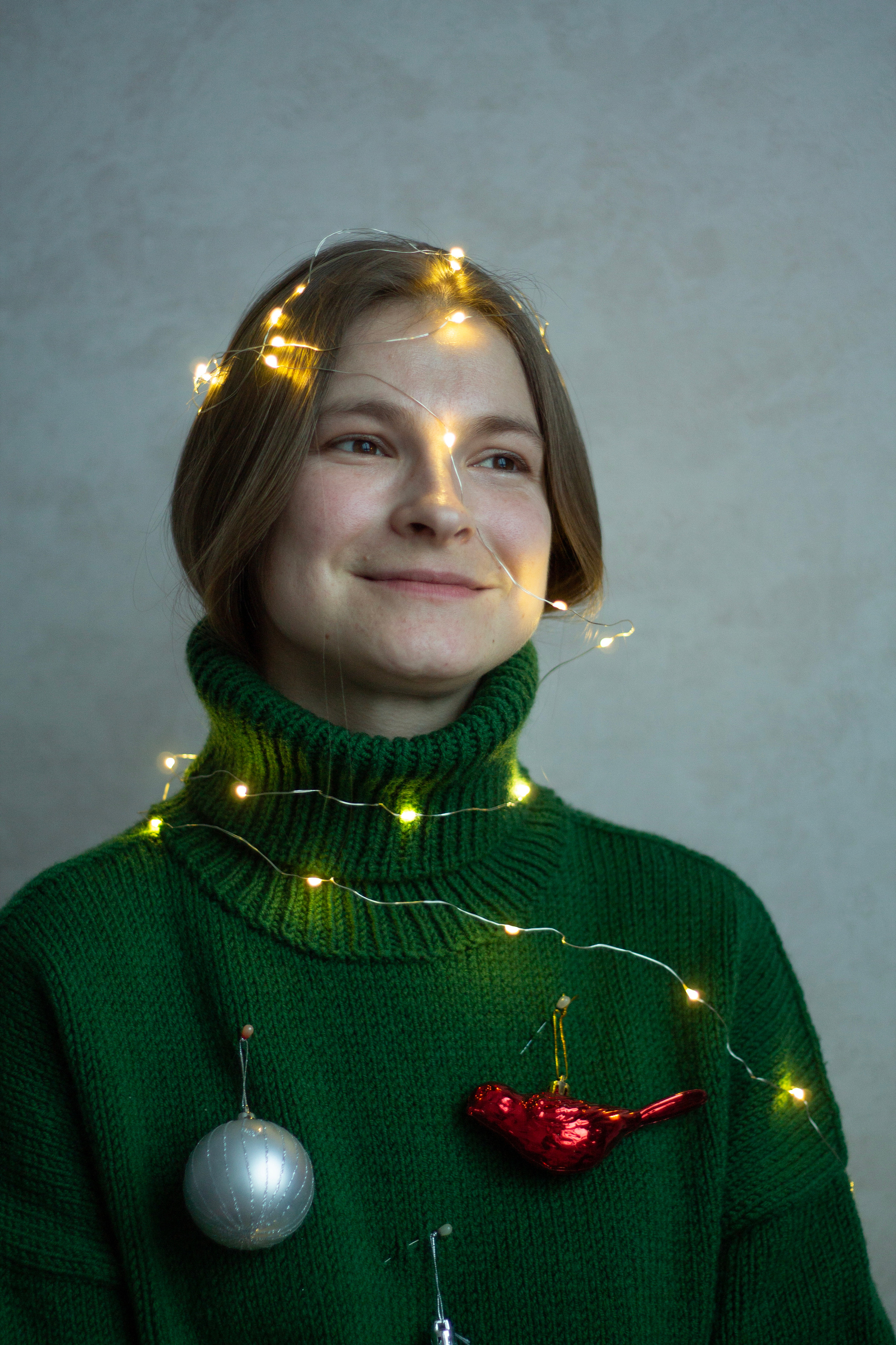 портрет девушки в зеленом свитере с новогодними украшениями