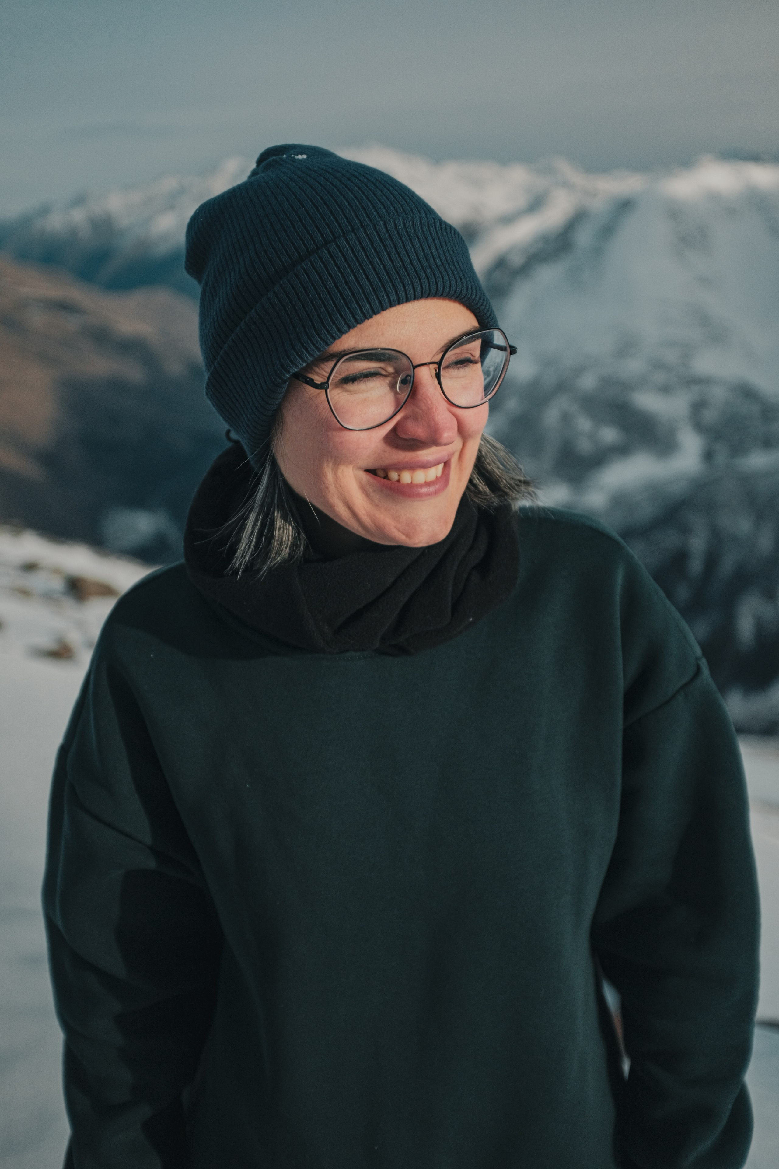 Портрет девушки в шапке и очках в горах Приэльбрусья зимой