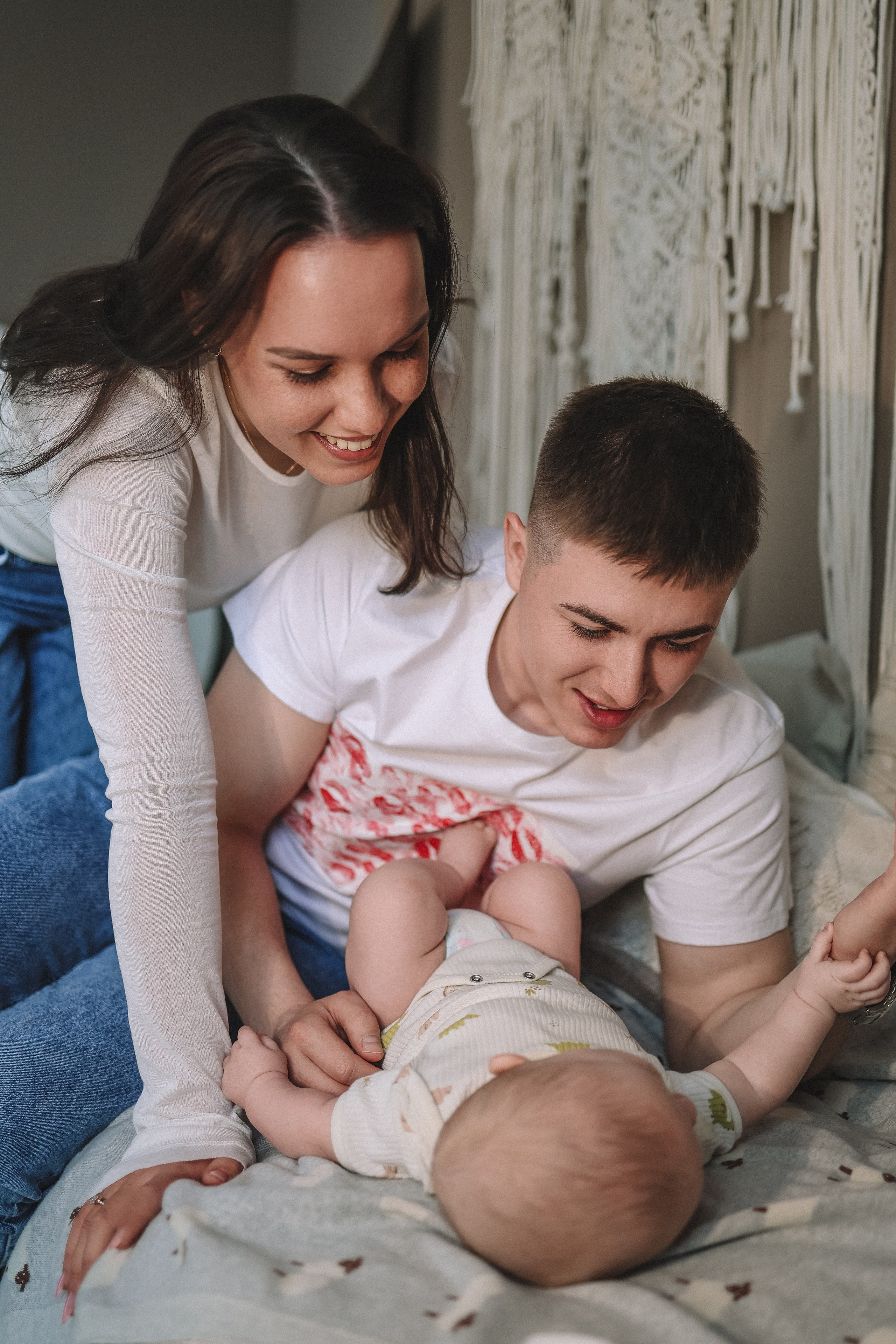 Родители улыбаются и обнимают малыша в домашней обстановке студии