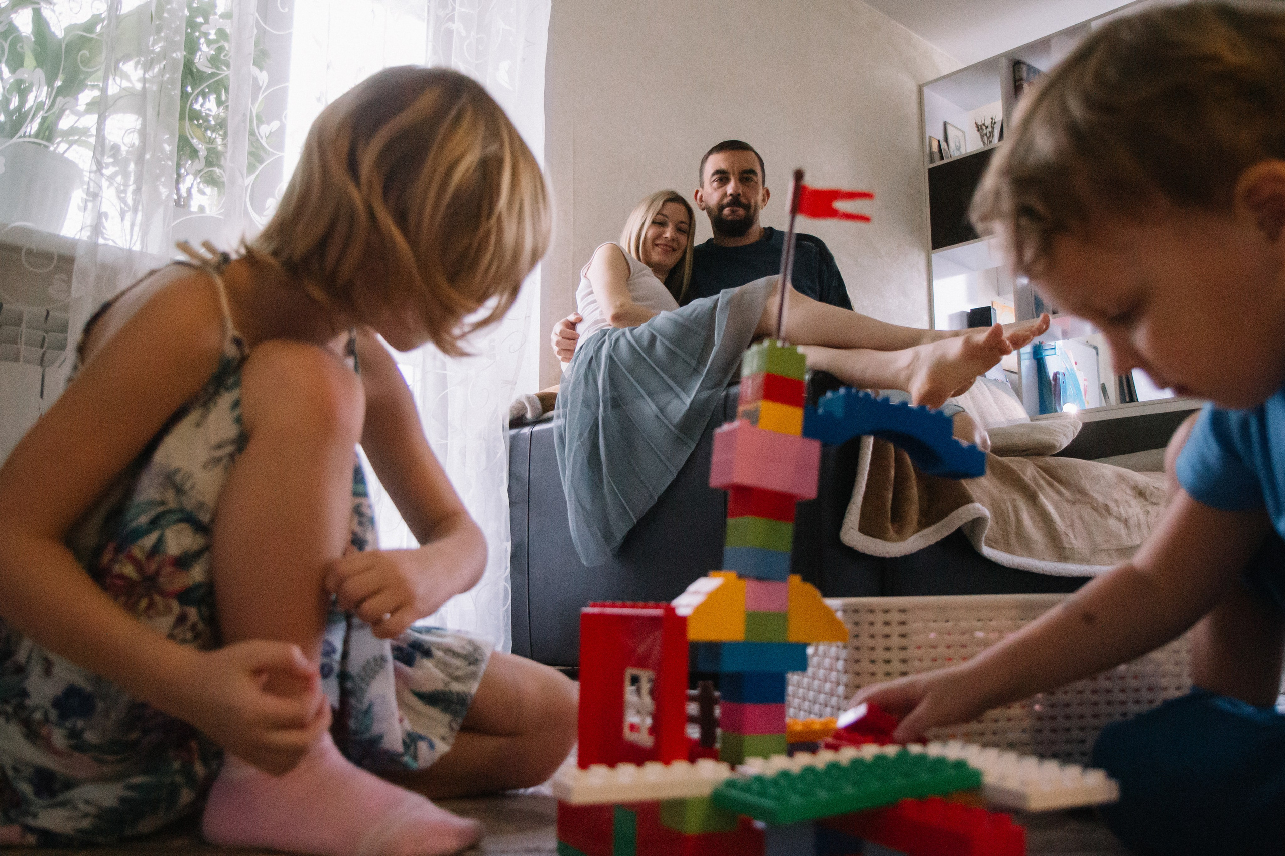 Дети играют в конструктор на фоне родителей