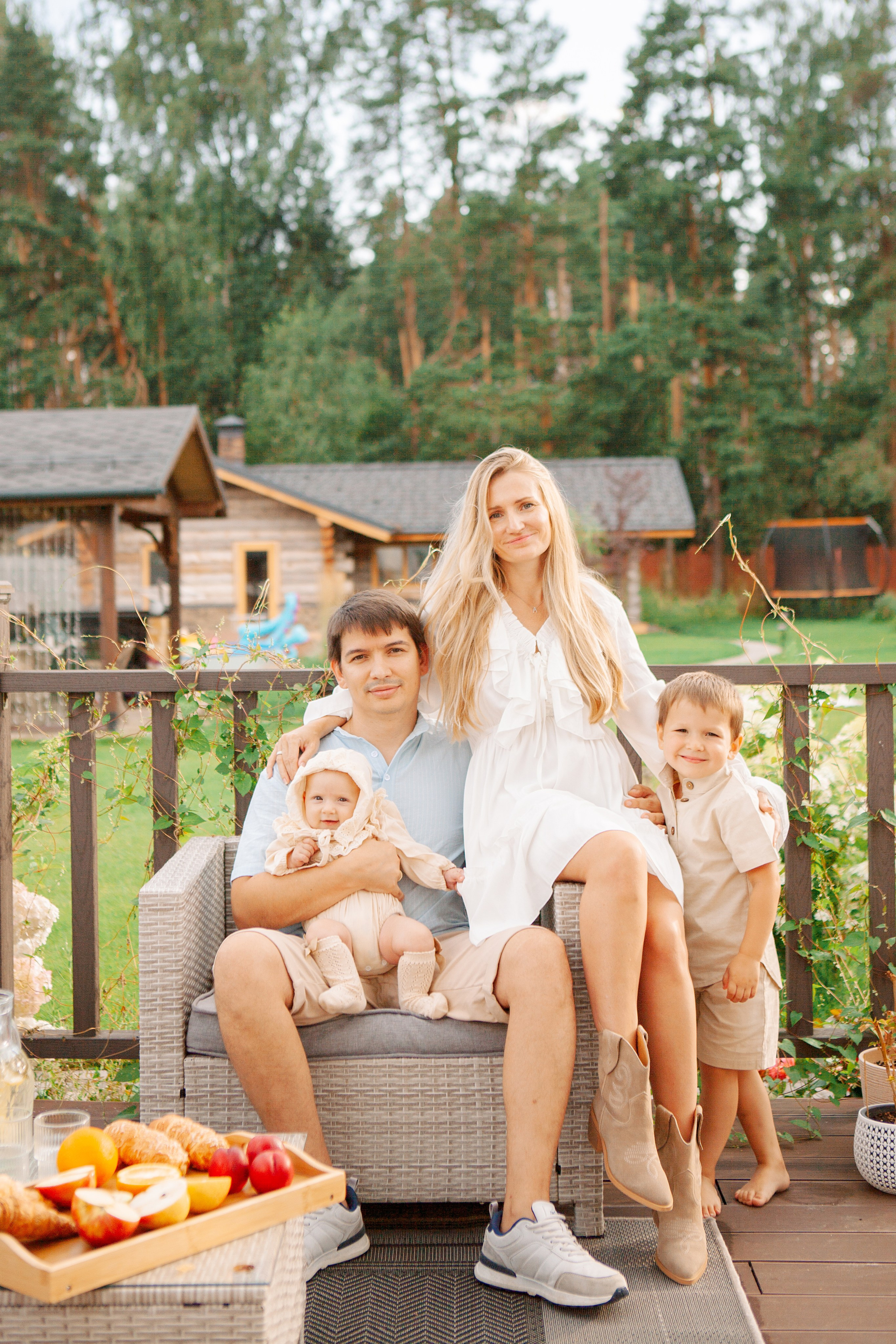 Семья с детьми на веранде собственного дома улыбаются и обнимаются