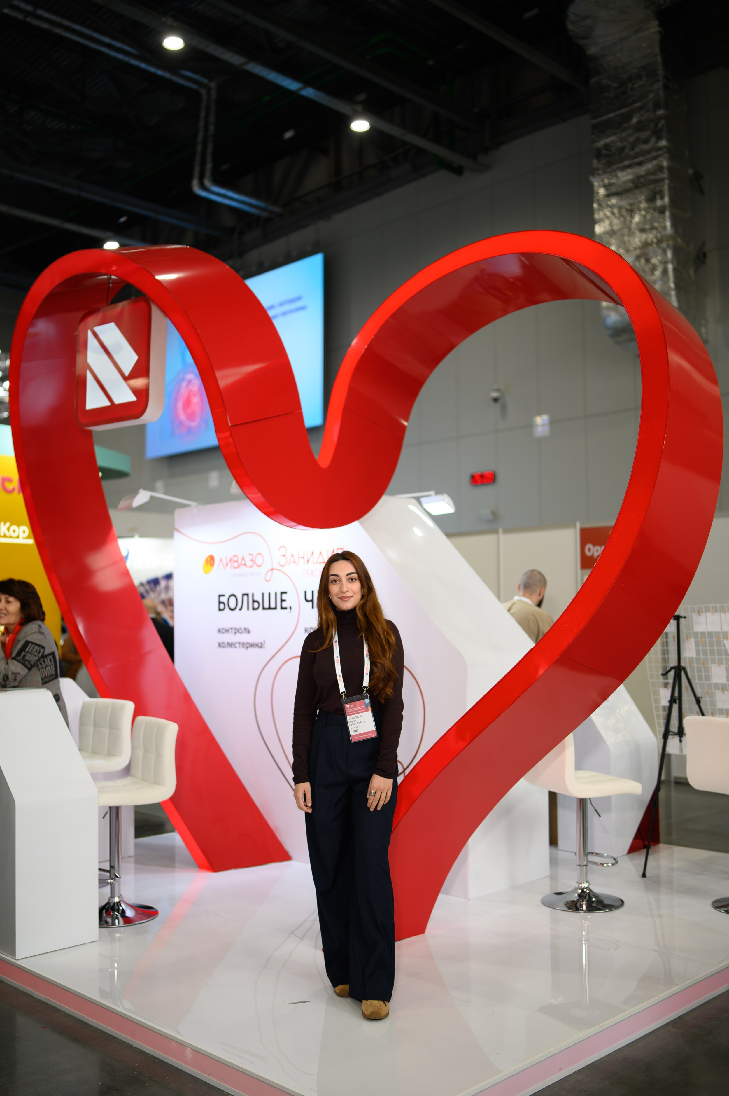 Женщина у стенда с символикой сердца, репортажная фотосъемка от Алексея Клейменова, Казань Экспо