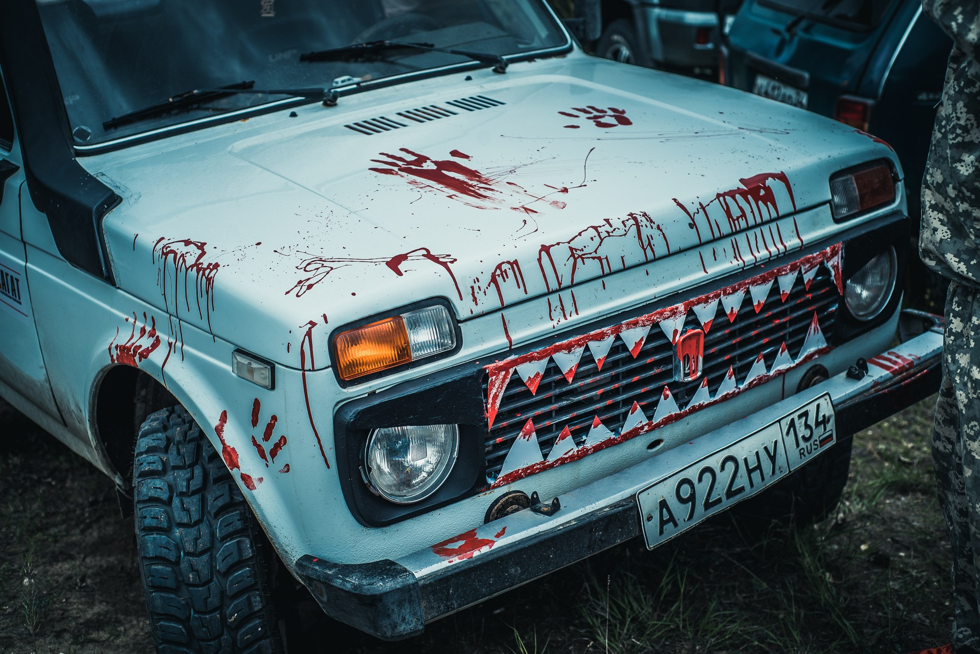 Белый автомобиль Нива с акульими зубами в крови на радиаторной решётке