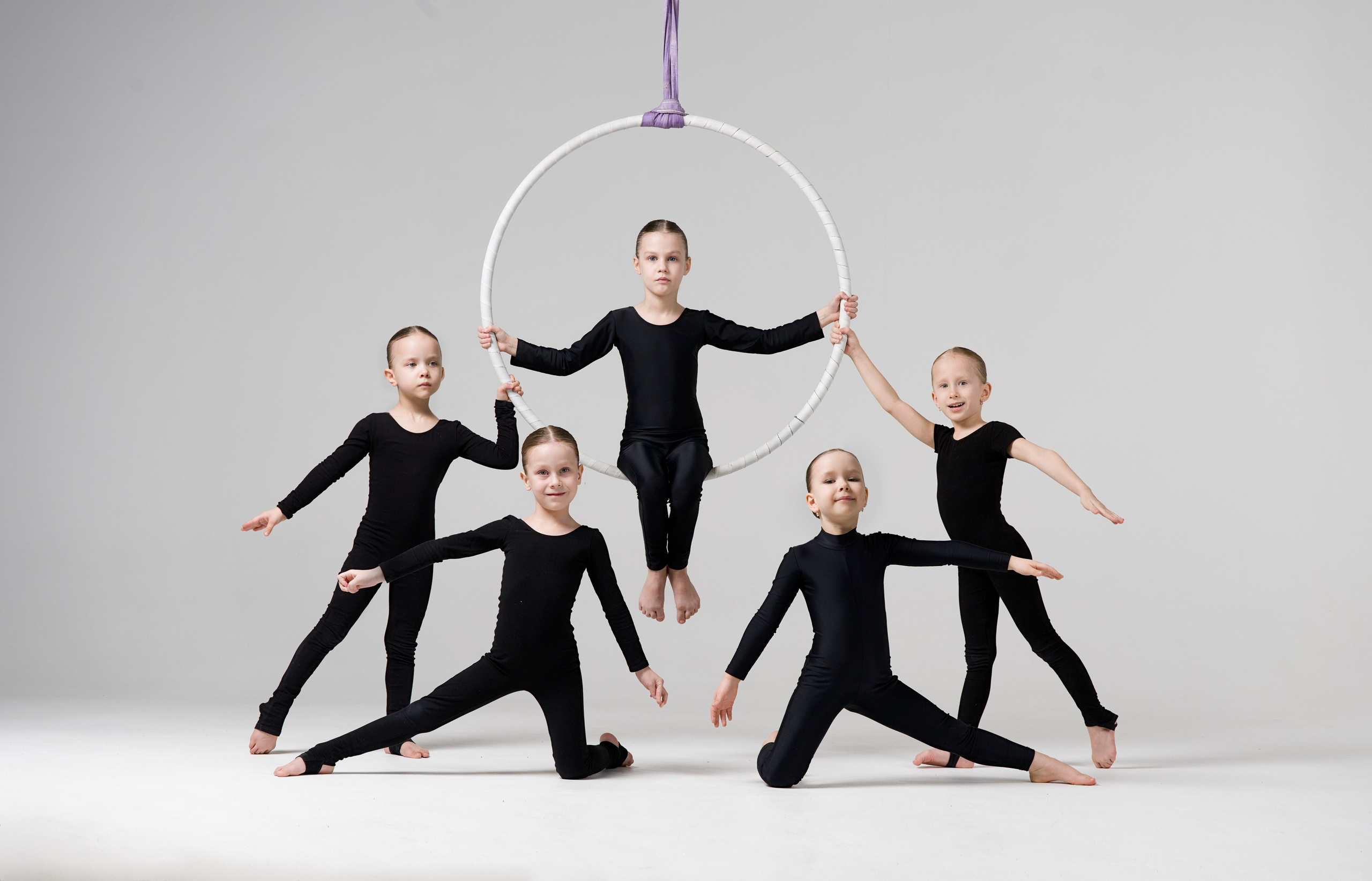 Спортивная мини-группа позирует со снарядом на белой циклораме, сплоченность и дисциплина юных атлетов