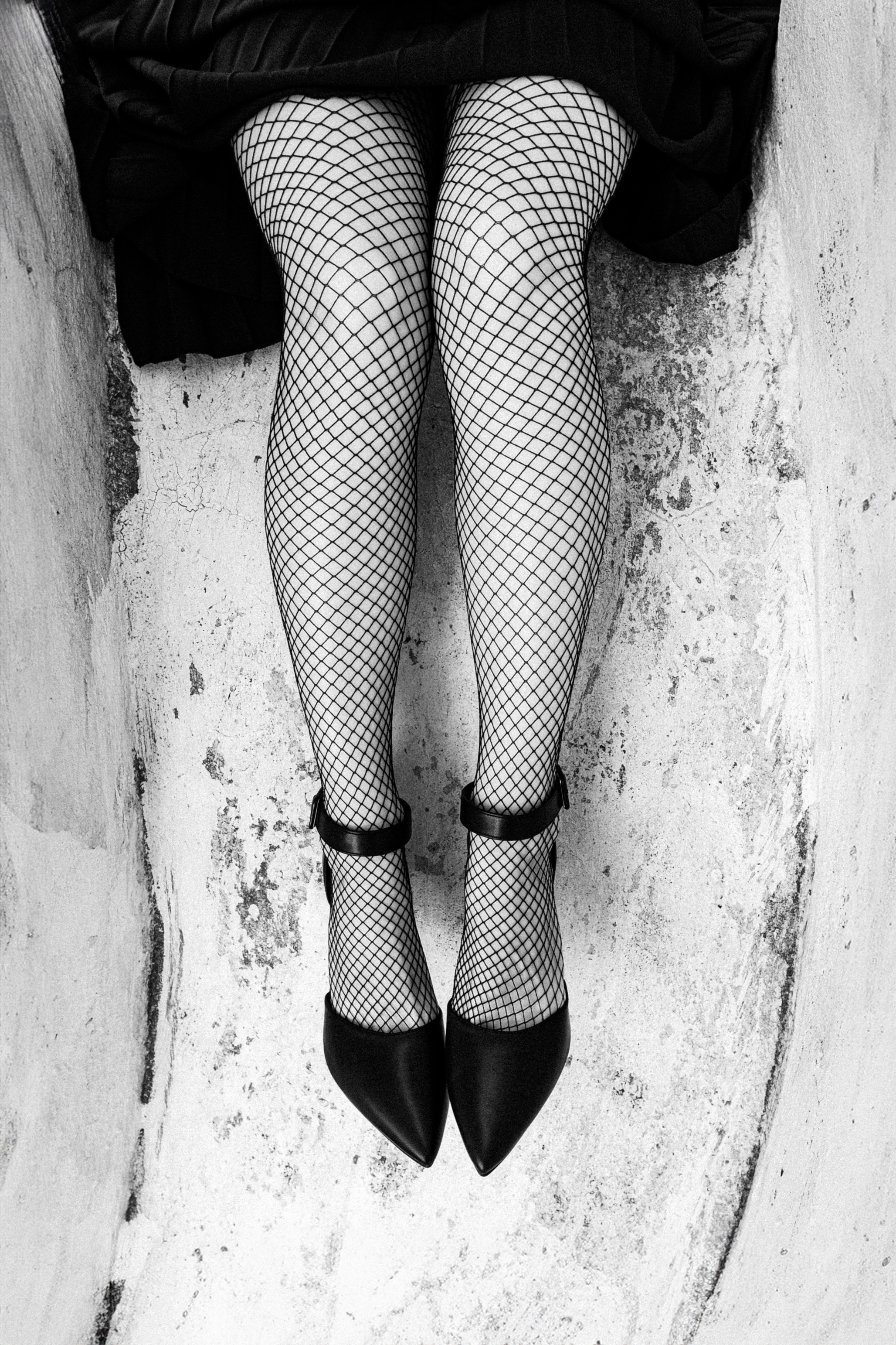 Женские ноги в сетчатых колготках и чёрных туфлях, художественная чёрно-белая съёмка с акцентом на текстуру и графику