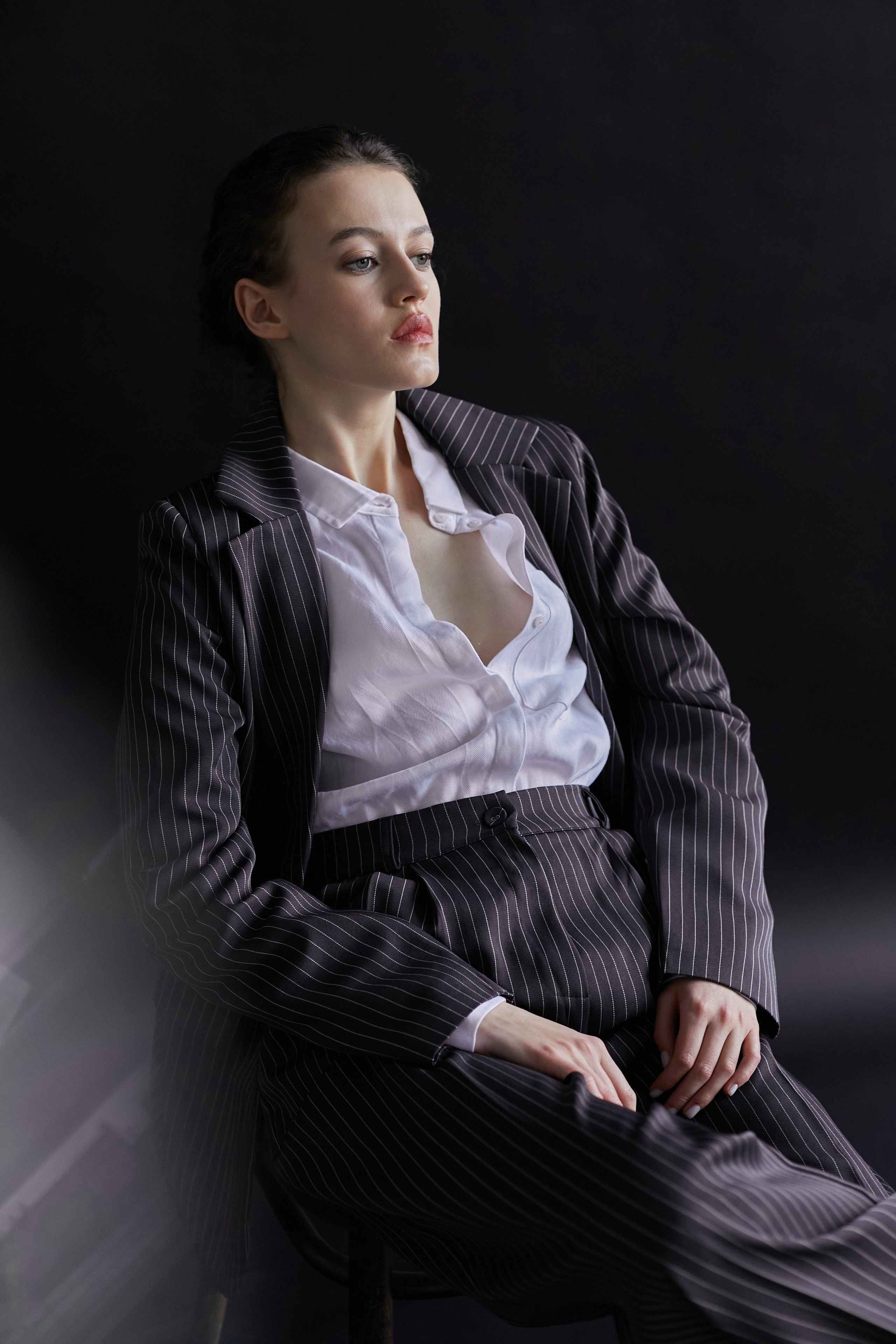Фотограф в Москве. Студия. Студийный портрет. Девушка в пиджаке. Девушка на стуле на черном фоне. Красивая девушка в мужском костюме. Женский портрет.