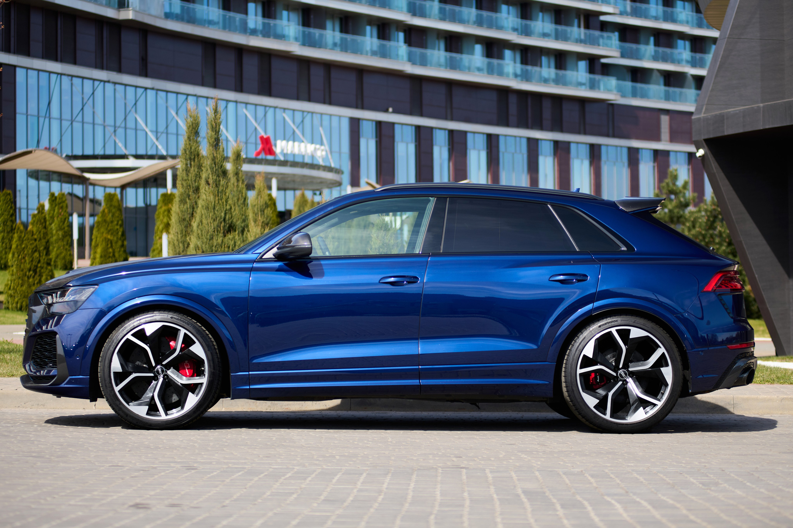 Синий Audi RS Q8 в профиль на городской парковке