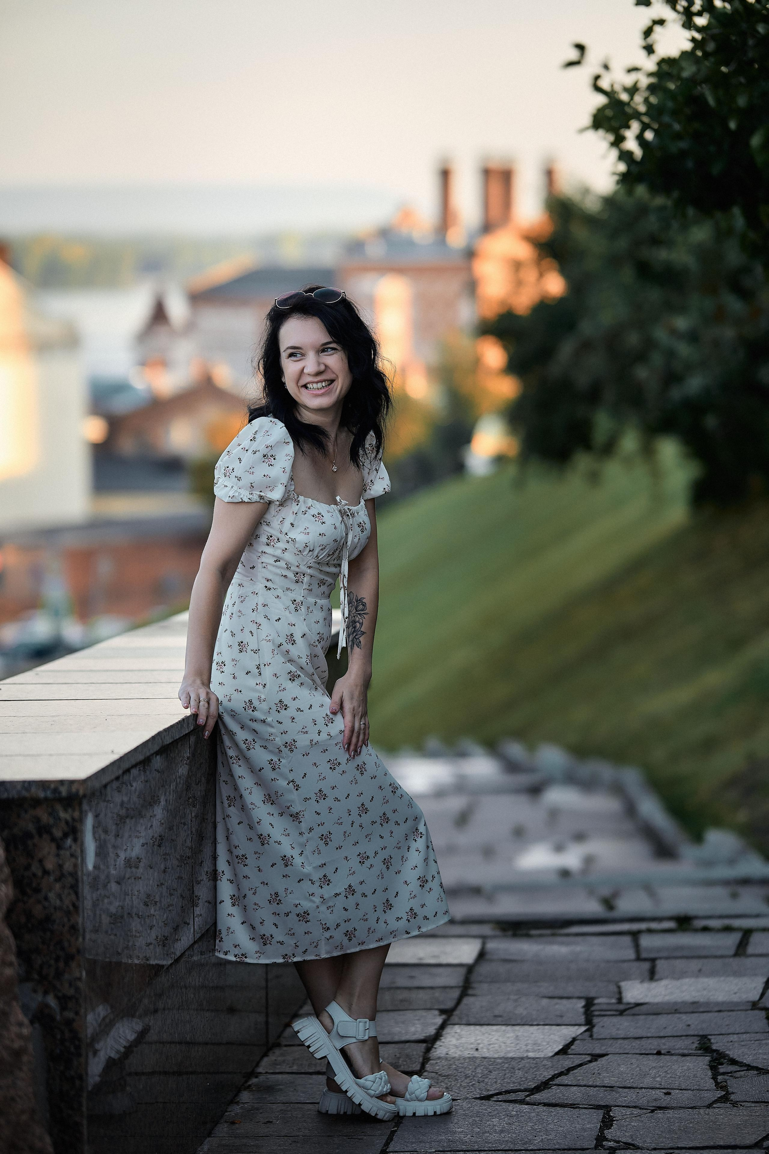 Женщина в летнем платье с городской архитектурой позади