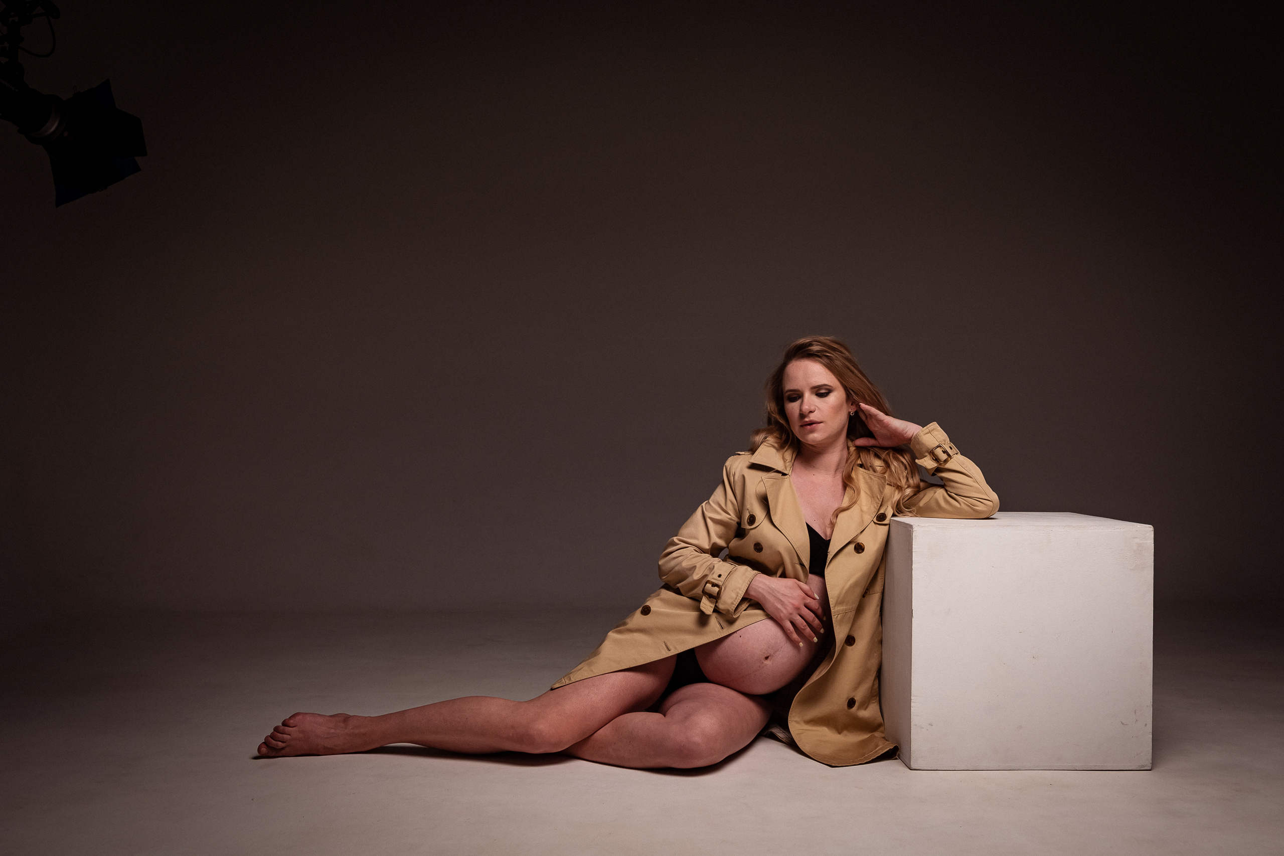 Беременная девушка в плаще на циклораме