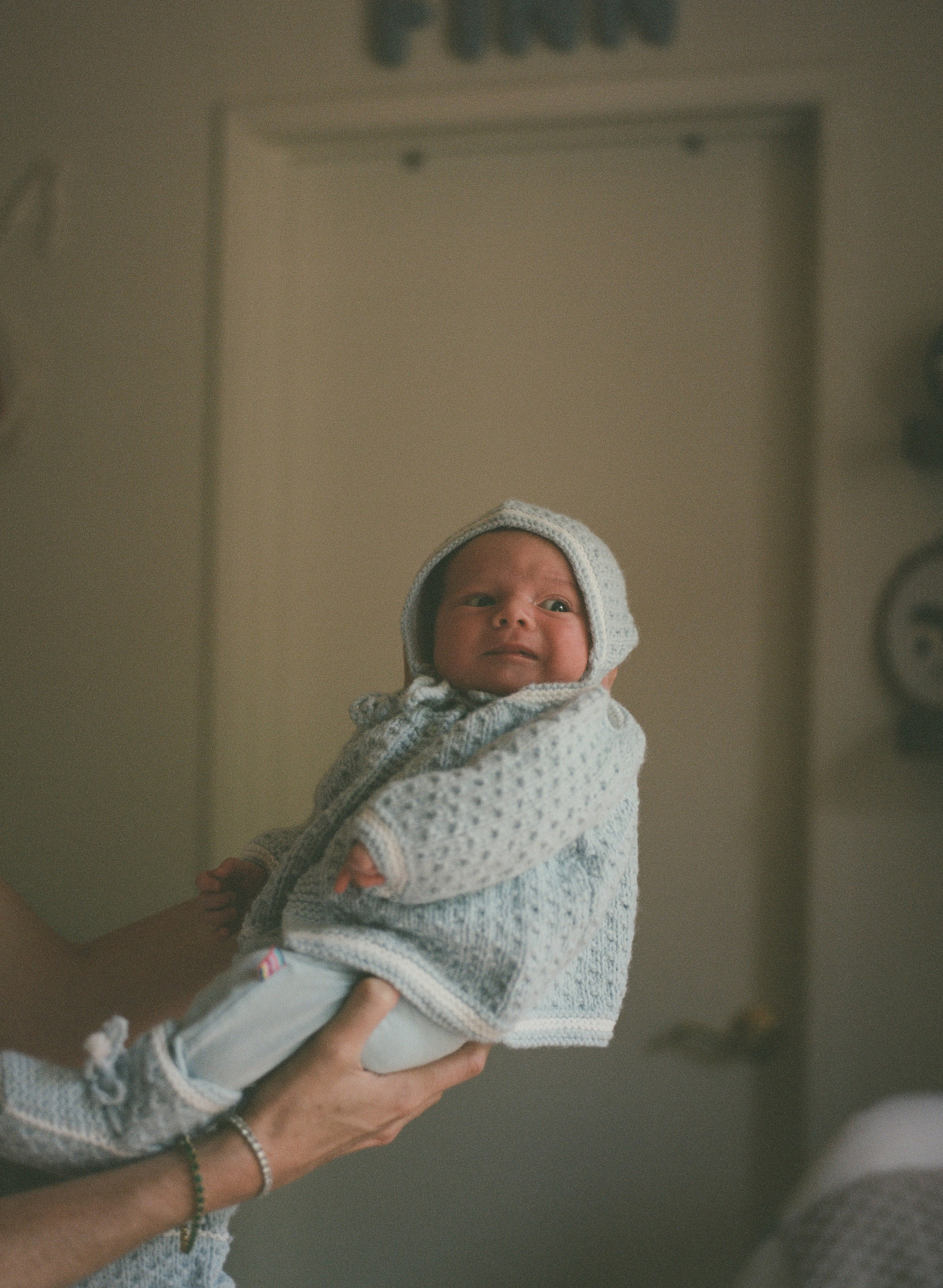 A father holding his baby boy up high, dressed in family heirloom clothes and captured on film in Venice, CA