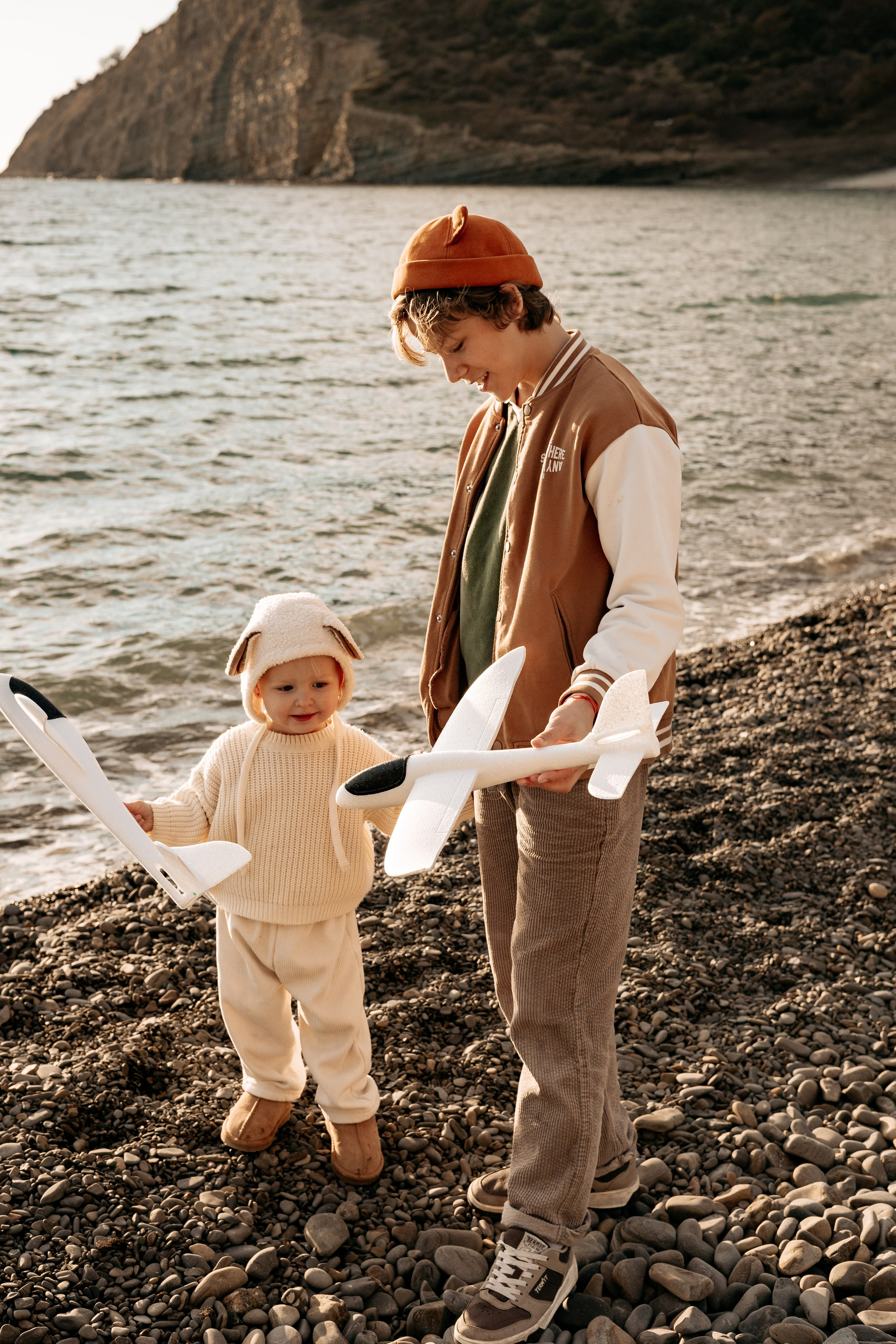 Родители учат детей запускать самолетики над морем