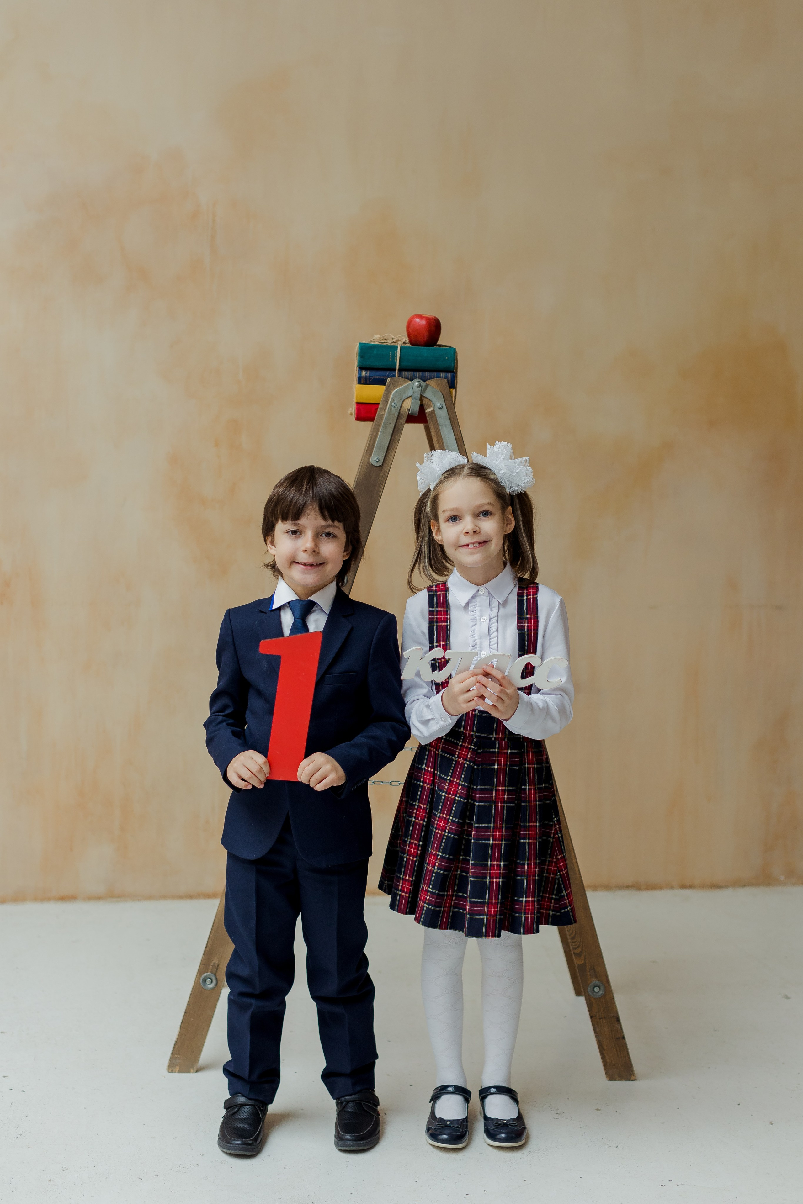 Мальчик и девочка стоят около лестницы с надписью 1 класс
