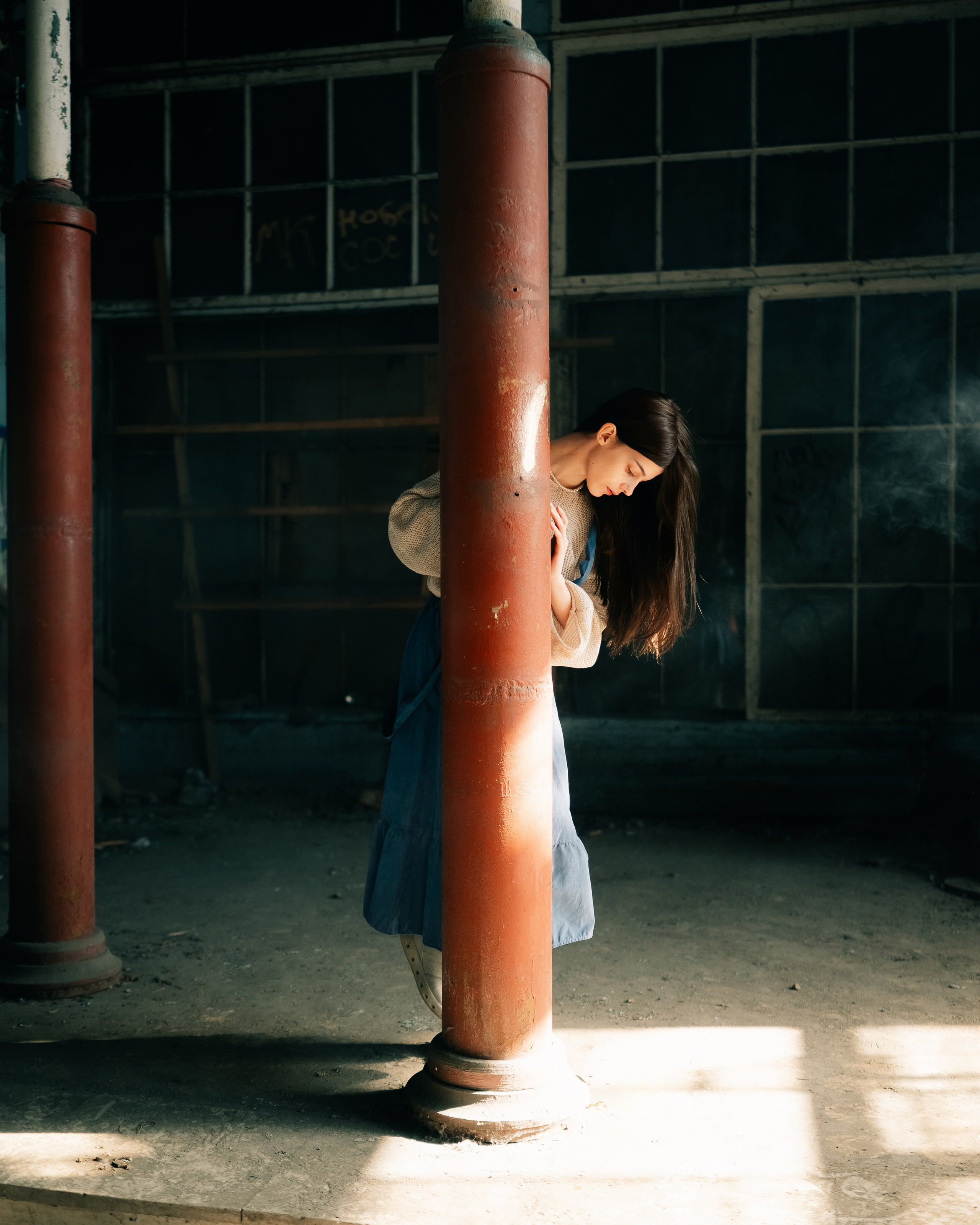 девушка задумчиво прячется за трубой в историческом здании
