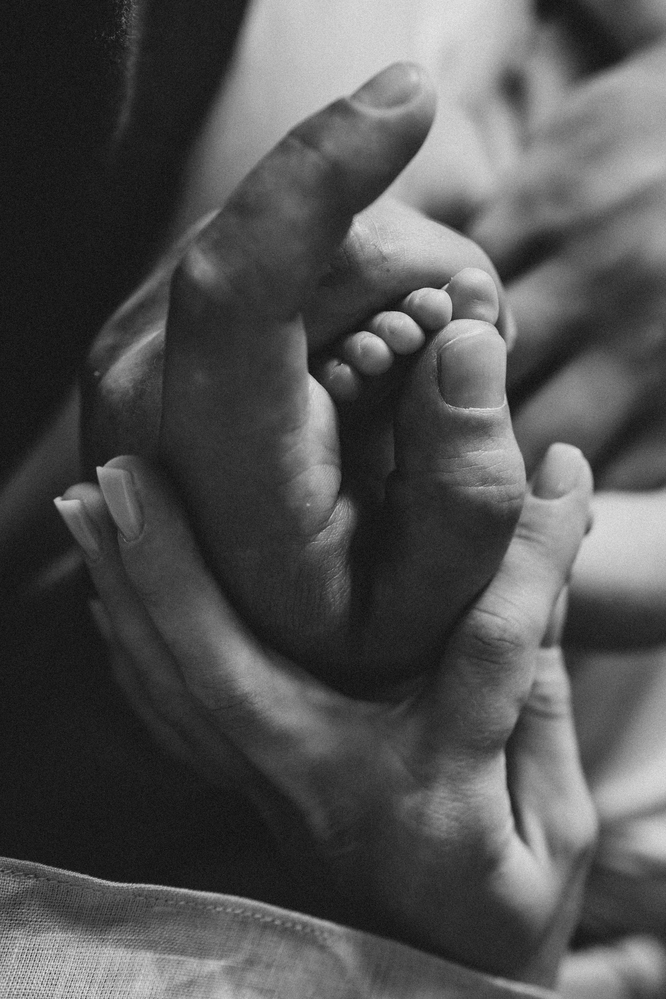Маленькая ручка новорождённого в руках родителей