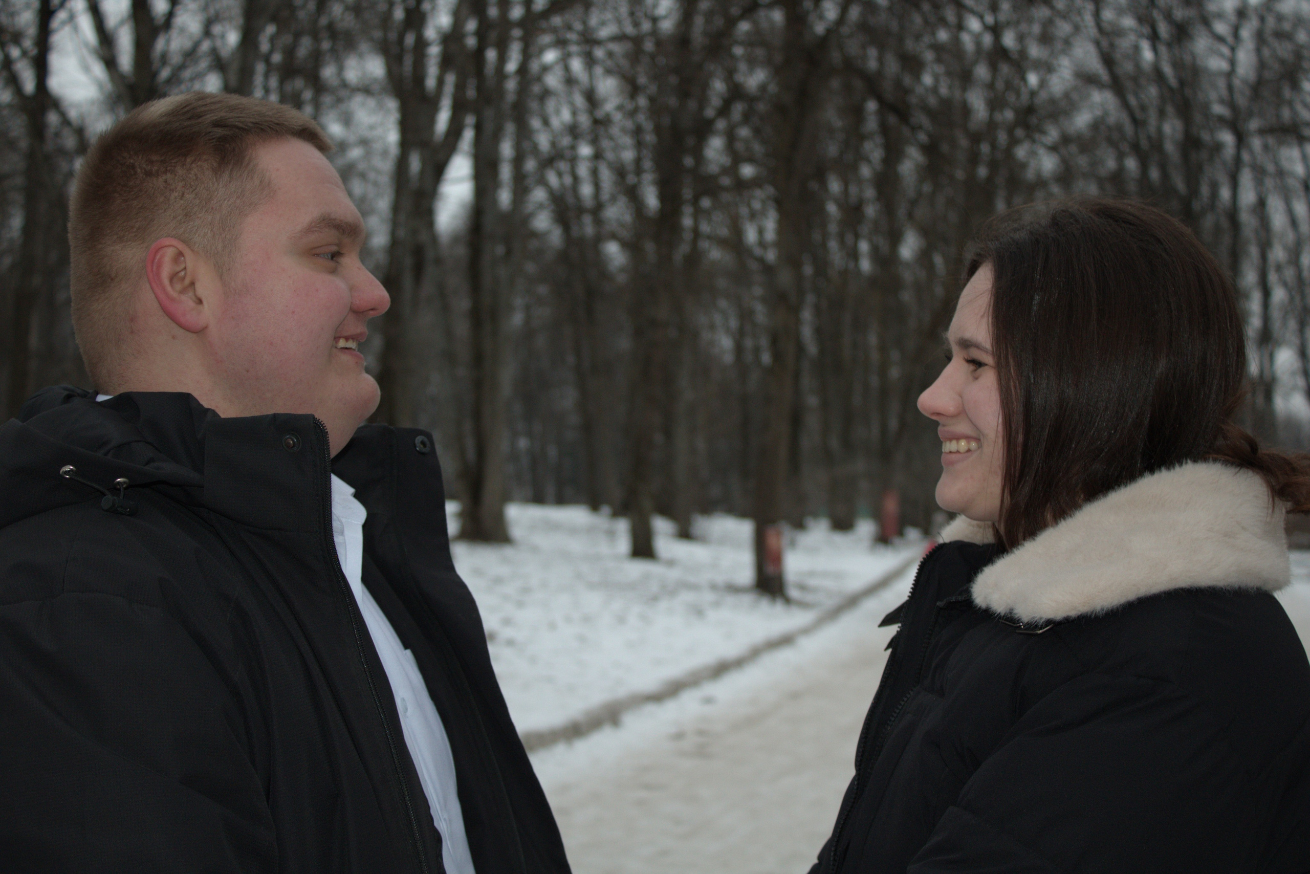 парень и девушка смотрят друг другу в глаза в зимнем парке